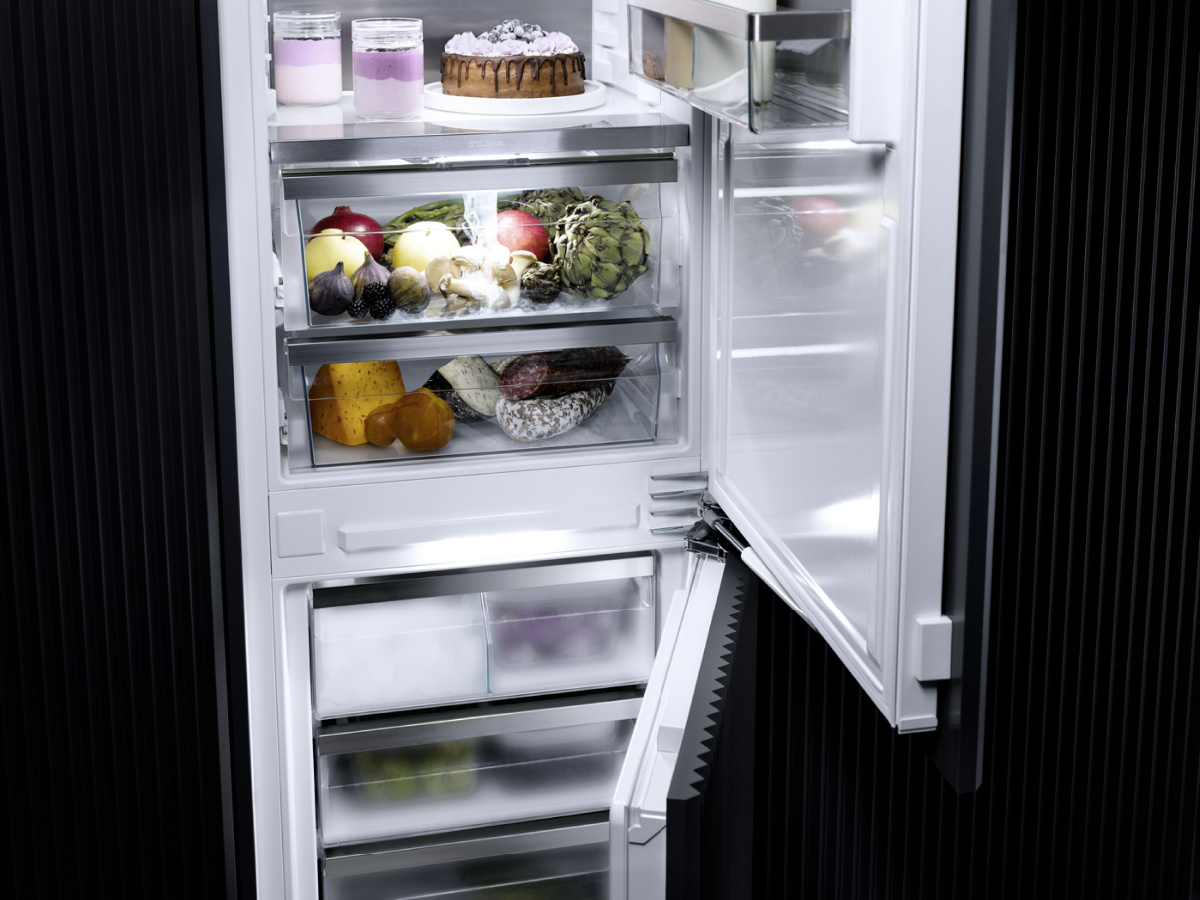 Intérieur de réfrigérateur, rempli d'aliments et éclairé, avec la porte partiellement ouverte.