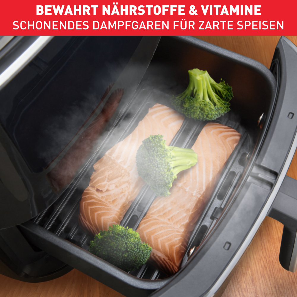 Lachs und Brokkoli werden in einem Grill gedämpft. Schwarzer Grill und dunkler Hintergrund.