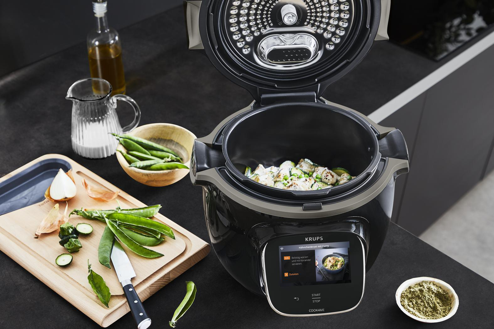 Küche mit einem Slow Cooker auf der Theke. Gemüse wird zubereitet.