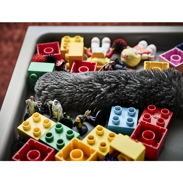 Eine Schale mit bunten Lego-Steinen, Figuren und einem Mikrofon in einem Raum.