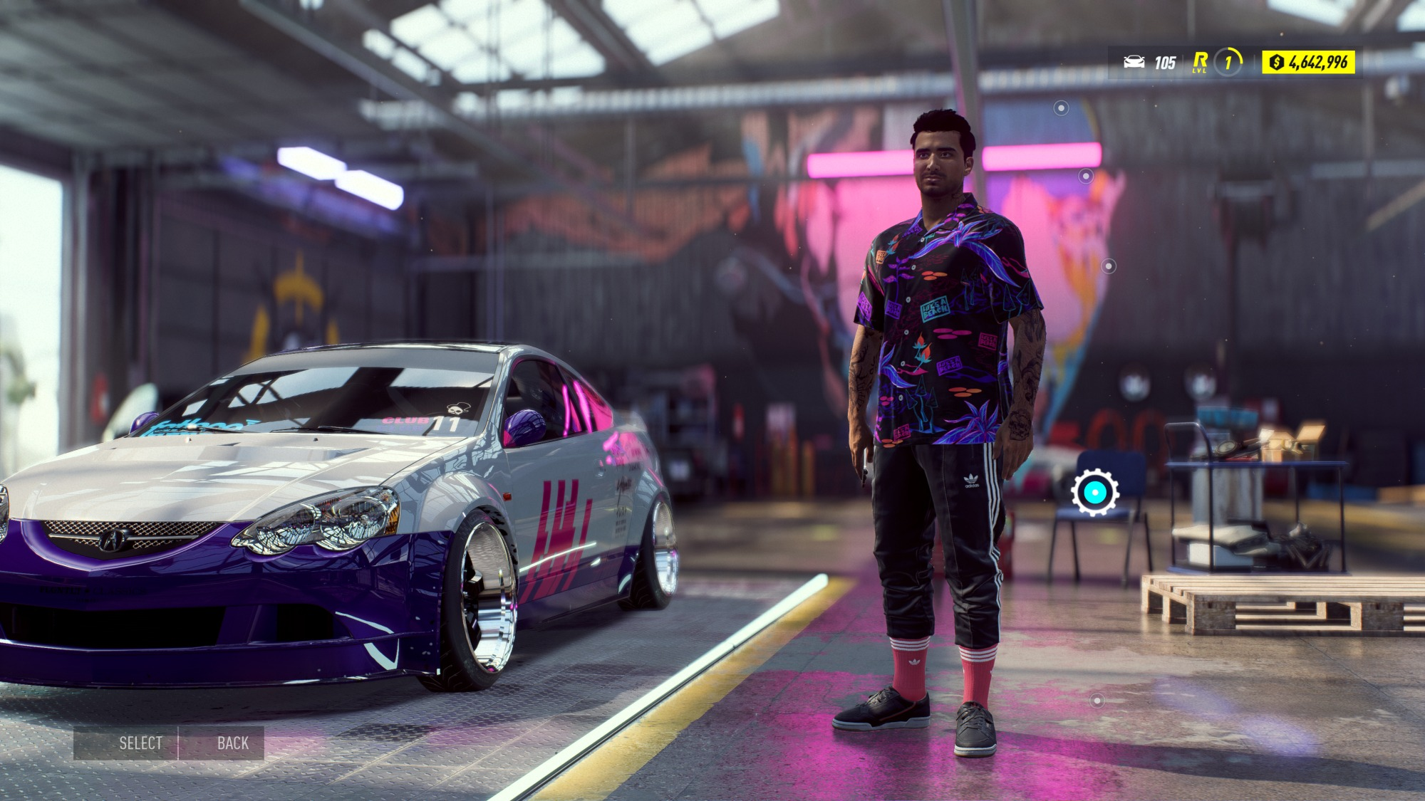 Mann steht neben einem lila Auto in einer Garage. Er trägt ein gemustertes Hemd und Adidas-Hosen.