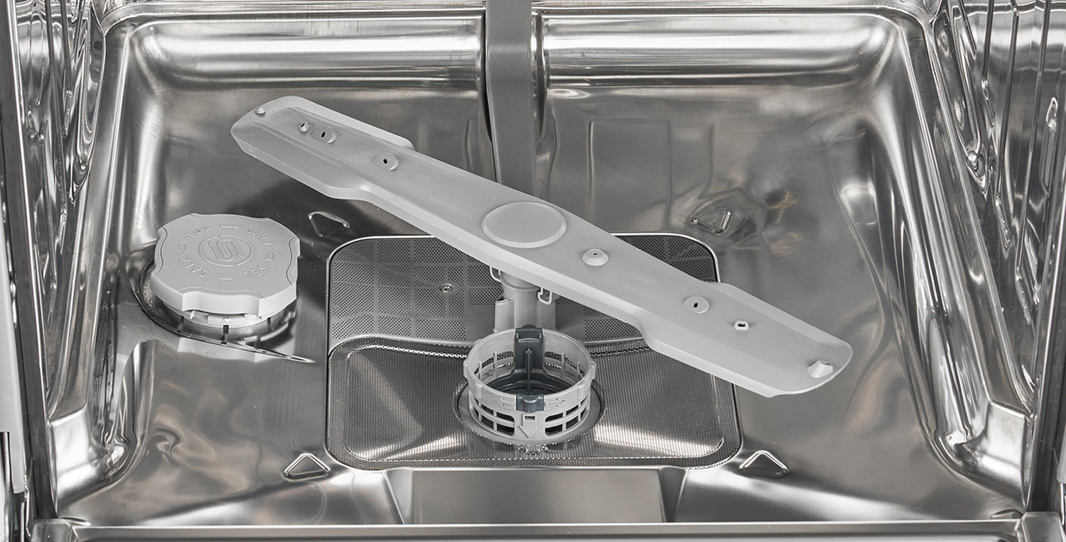 Inside of a dishwasher. There is a sprayer and a filter. The inside is stainless steel.