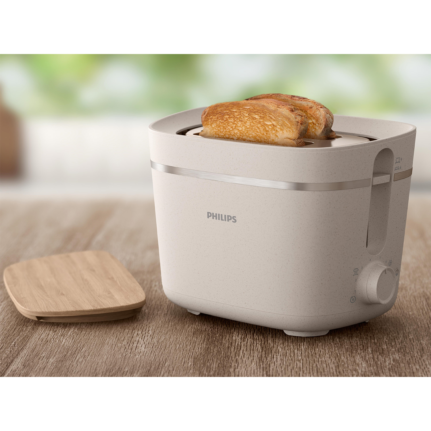 Tostapane bianco sporco con due fette di pane tostato all'interno. Coperchio in legno accanto.