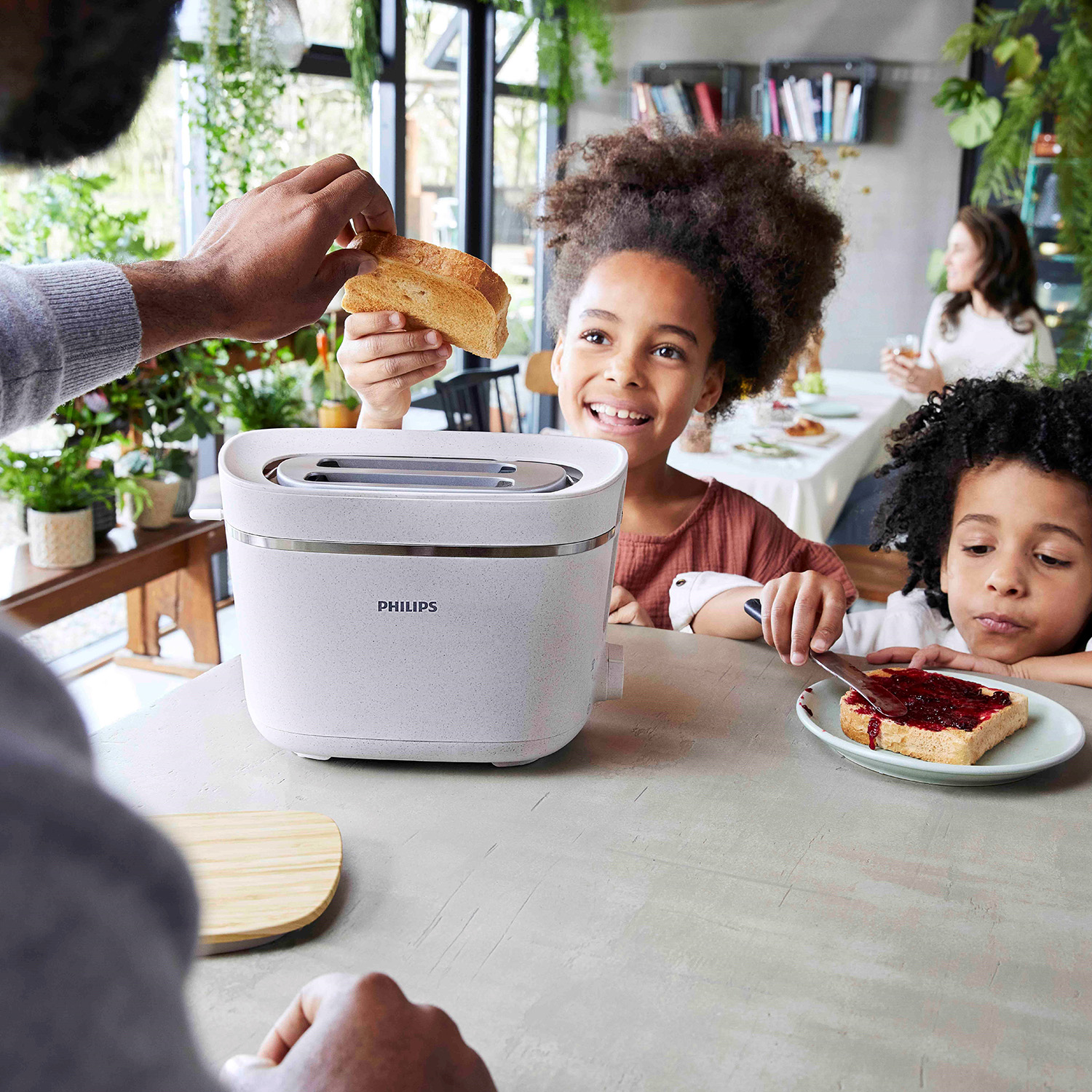 Una famiglia tosta il pane con un tostapane Philips, i bambini sono seduti e mangiano.