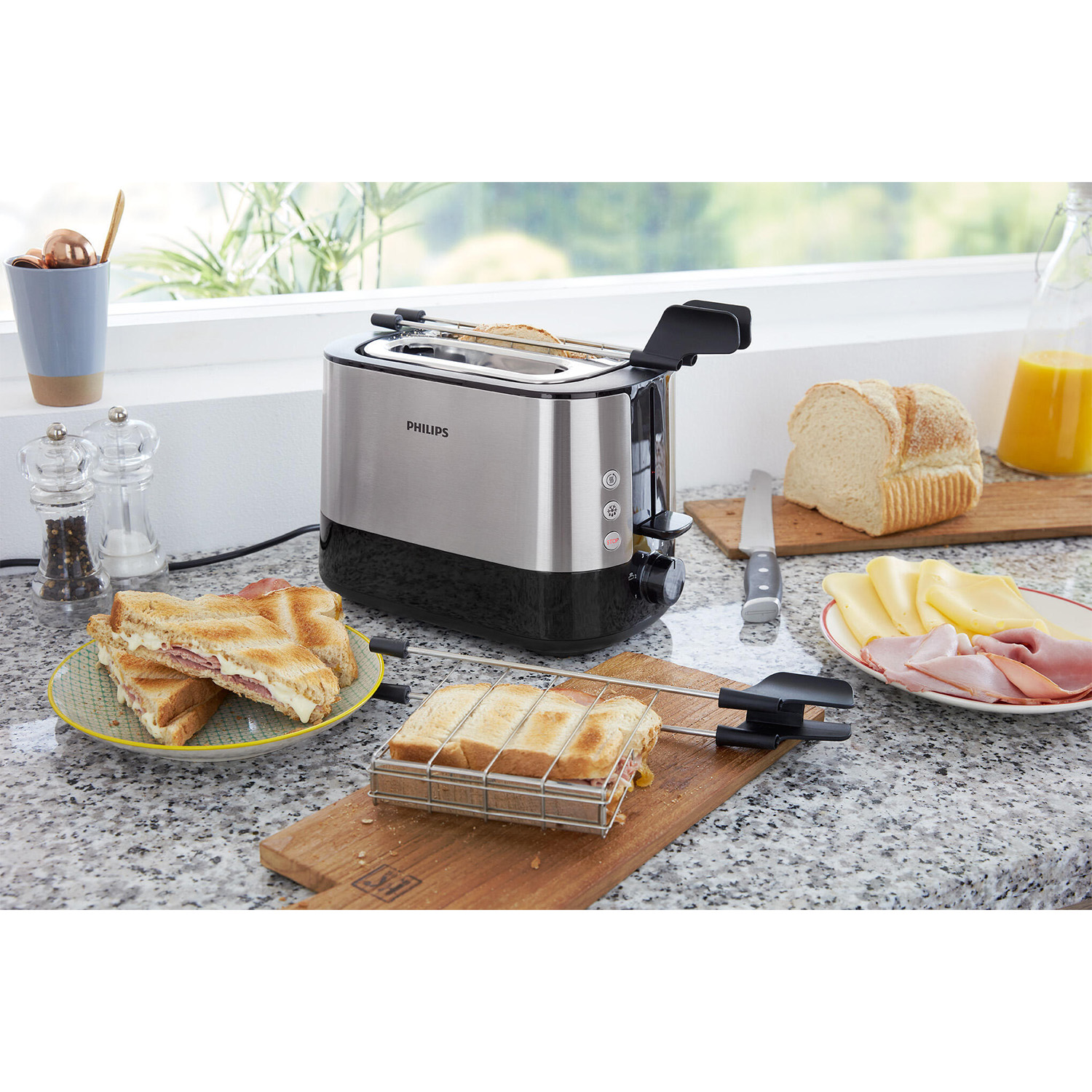 Un tostapane con due fette di pane tostato. Sono visibili anche panini, formaggio, prosciutto e un coltello.