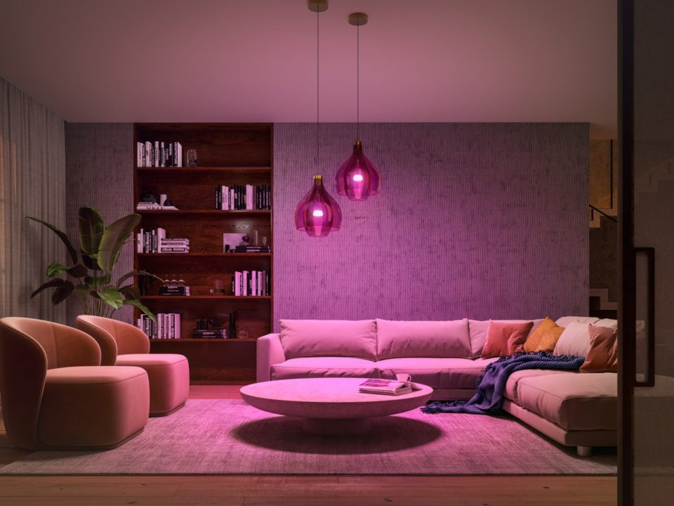 Soggiorno moderno con illuminazione rosa. Divano, sedie, libri e tappeto sono visibili.