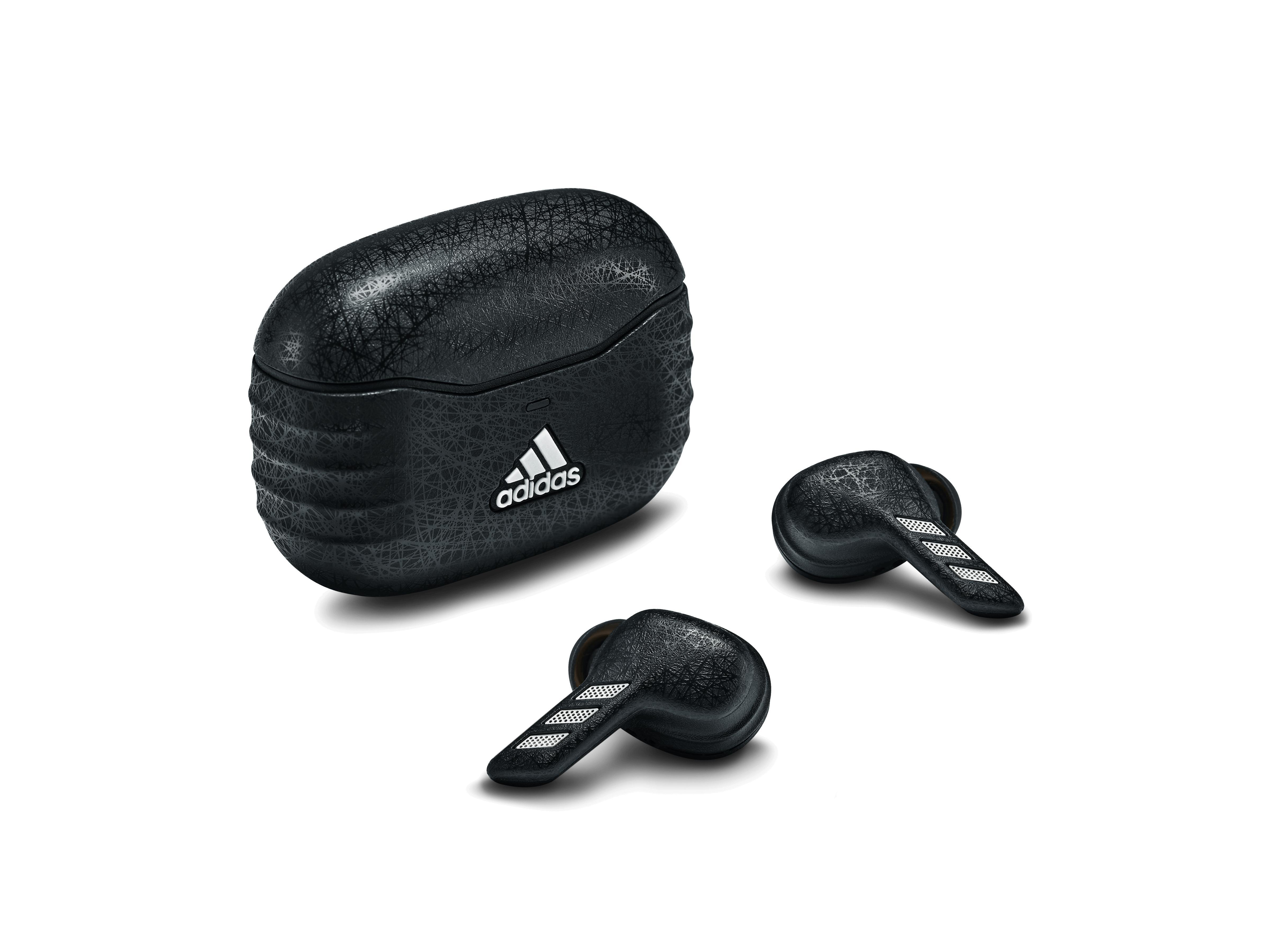 Schwarze Adidas-Ohrhörer, Ladecase mit Adidas-Logo, alles vor weißem Hintergrund. Strukturiertes Design.