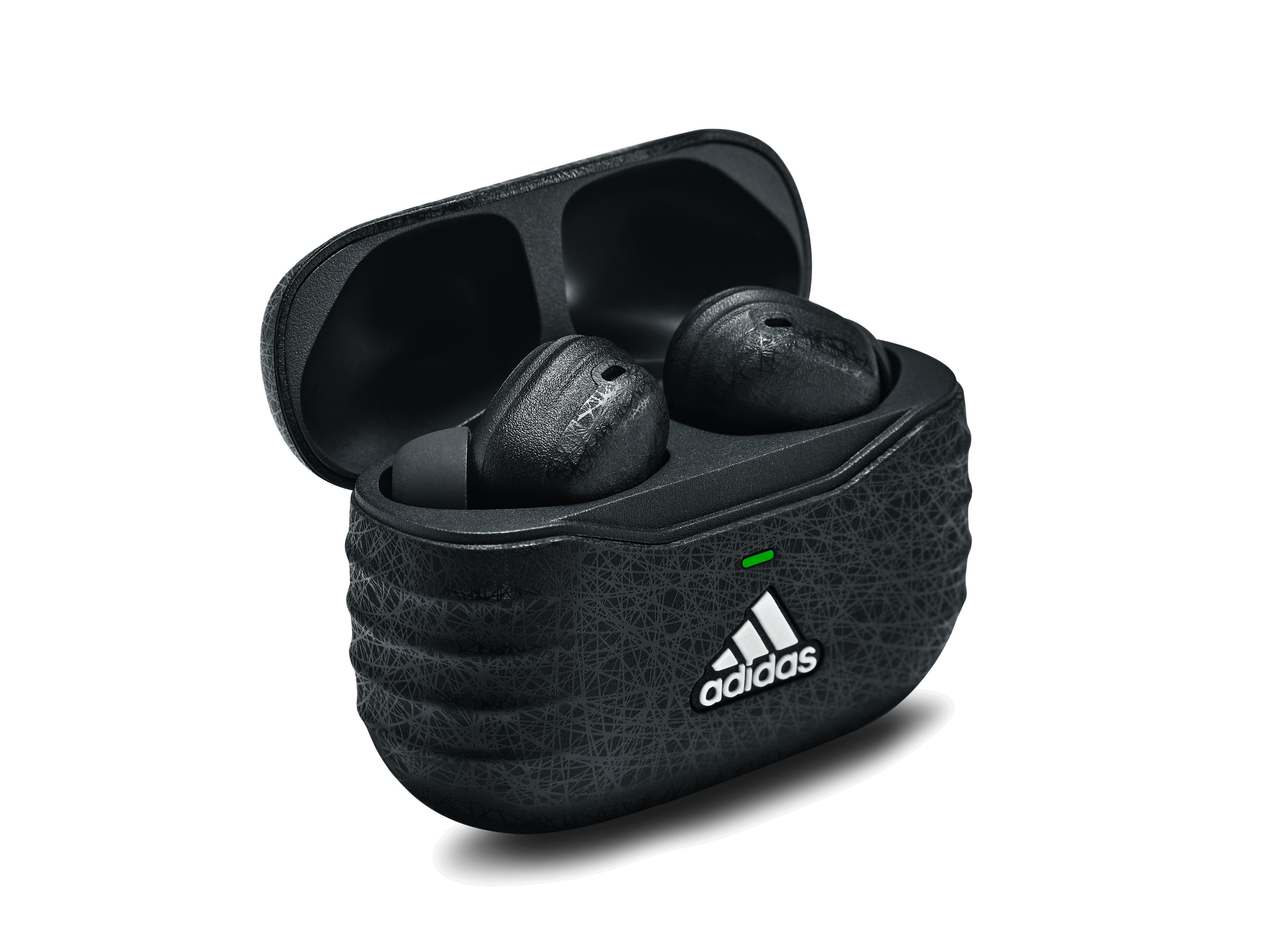 Schwarze Adidas-Ohrhörer in einem Etui. Das Etui ist offen und zeigt die Ohrhörer. Adidas-Logo auf dem Etui.