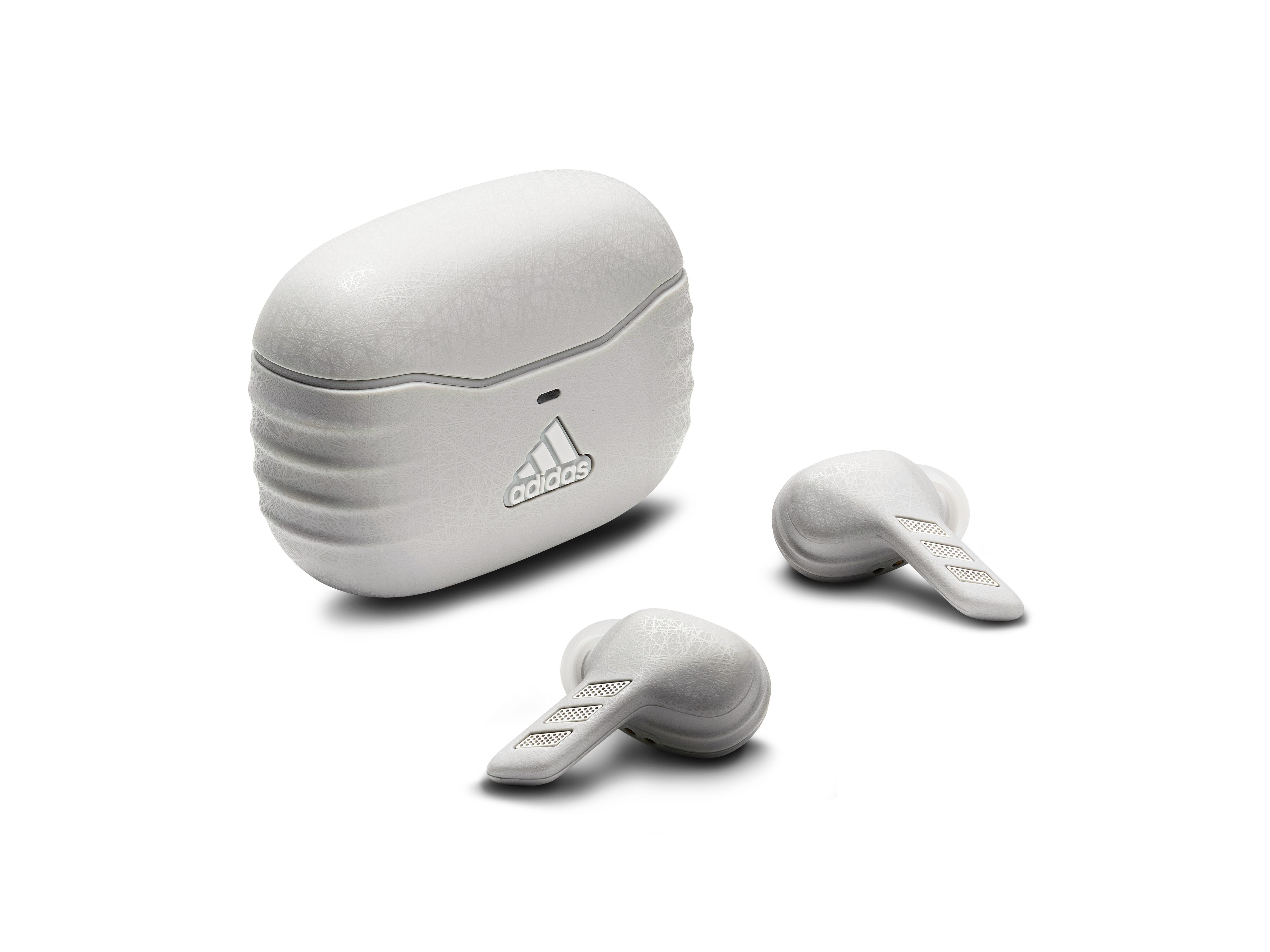 Weiße Adidas-Ohrhörer und Ladecase auf weißer Oberfläche. Das Adidas-Logo ist sichtbar.