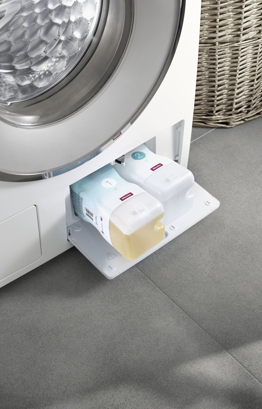 Waschmaschine mit Waschmittelflaschen in der Spülmittelschublade.