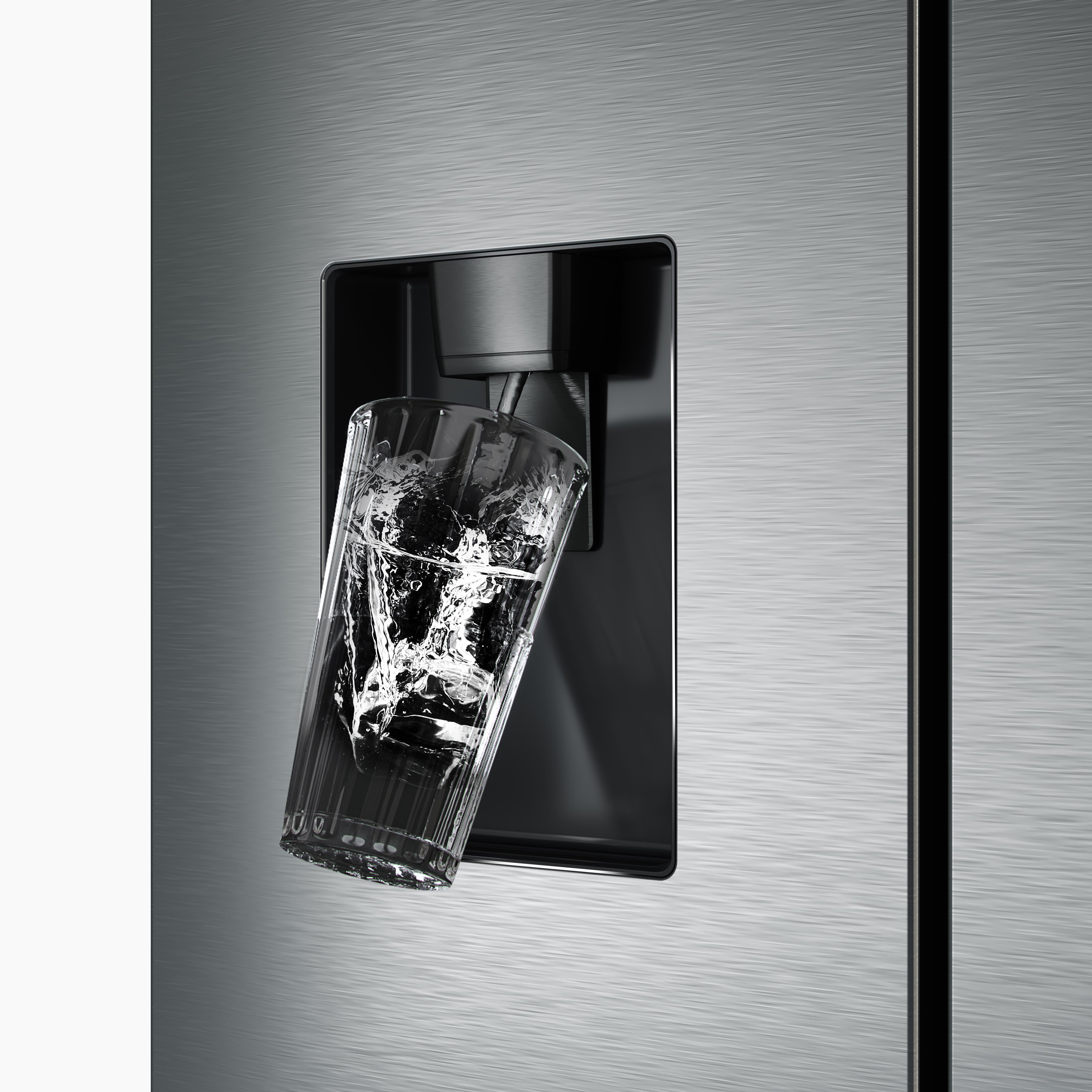 Ein Glas wird aus einem Spender mit Wasser gefüllt. Der Hintergrund ist eine metallische Kühlschranktür.