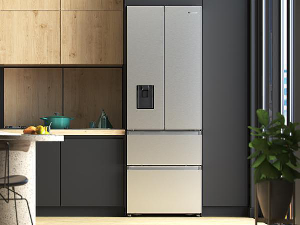 Eine moderne Küche mit einem großen Kühlschrank aus Edelstahl. Es gibt Holzschränke und eine dunkelgraue Wand.