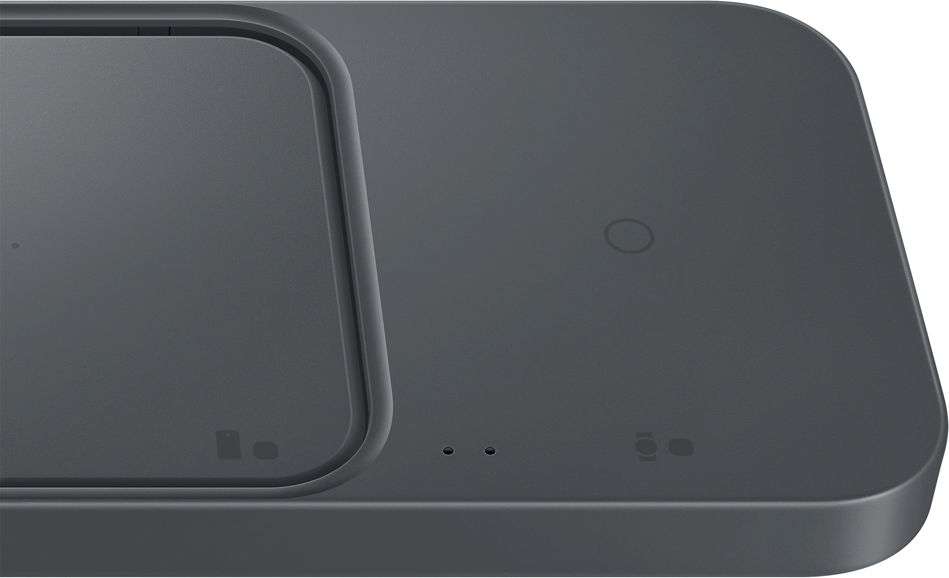 Közelkép egy sötétszürke vezeték nélküli töltőpadról. Két töltési terület, LED-ekkel.