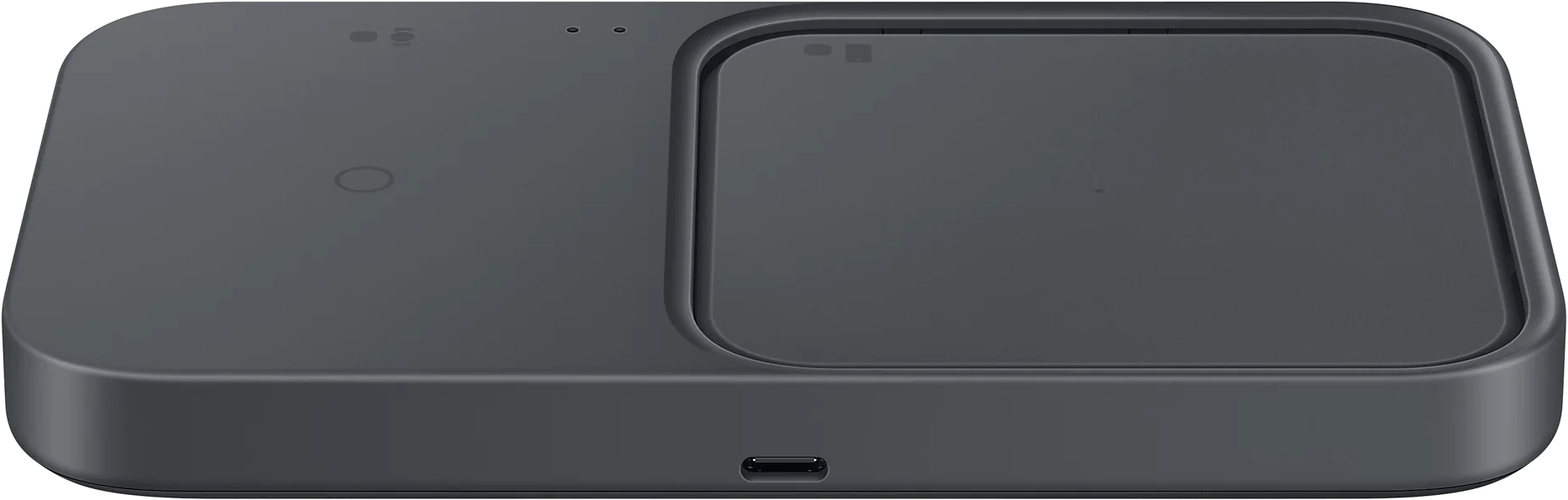 Fekete vezeték nélküli töltőpad, két töltési területtel és egy USB-C porttal fehér felületen.
