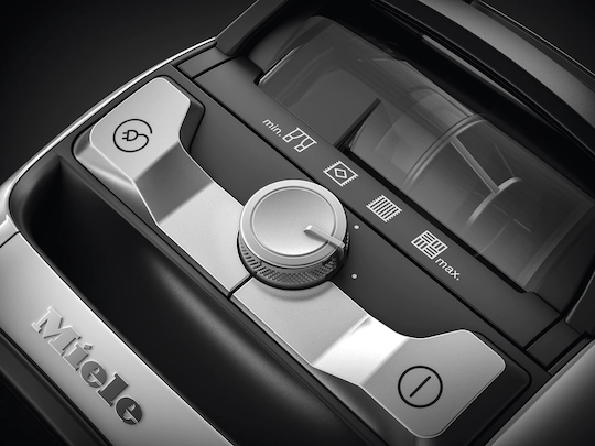 Bedieningspaneel van stofzuiger met knoppen en draaiknop, metallic details, Miele logo.