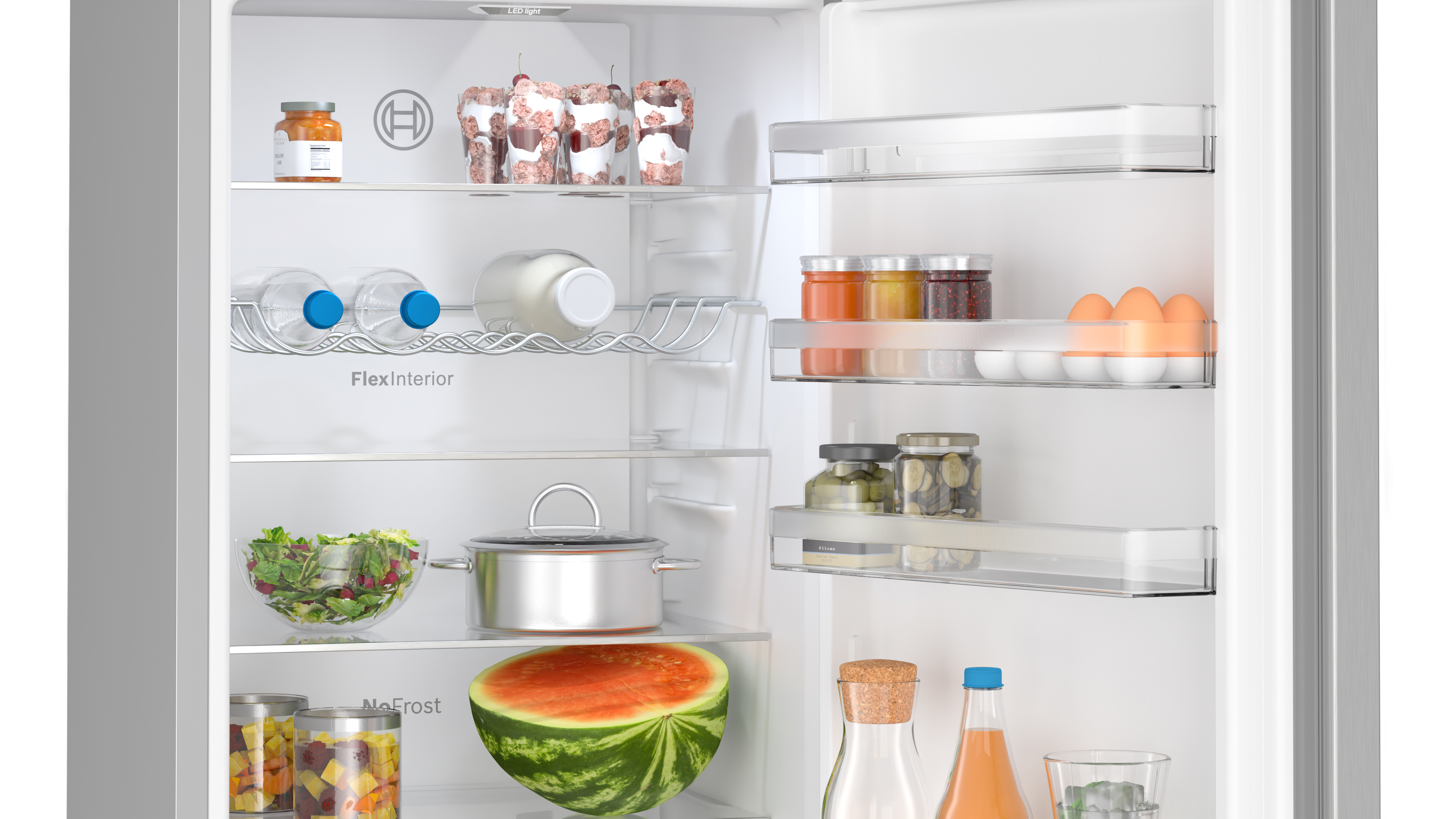 Kühlschrank-Innenraum: Lebensmittel auf Regalen, darunter Gläser, Wasserflaschen, Salat und eine Wassermelonen-Hälfte.