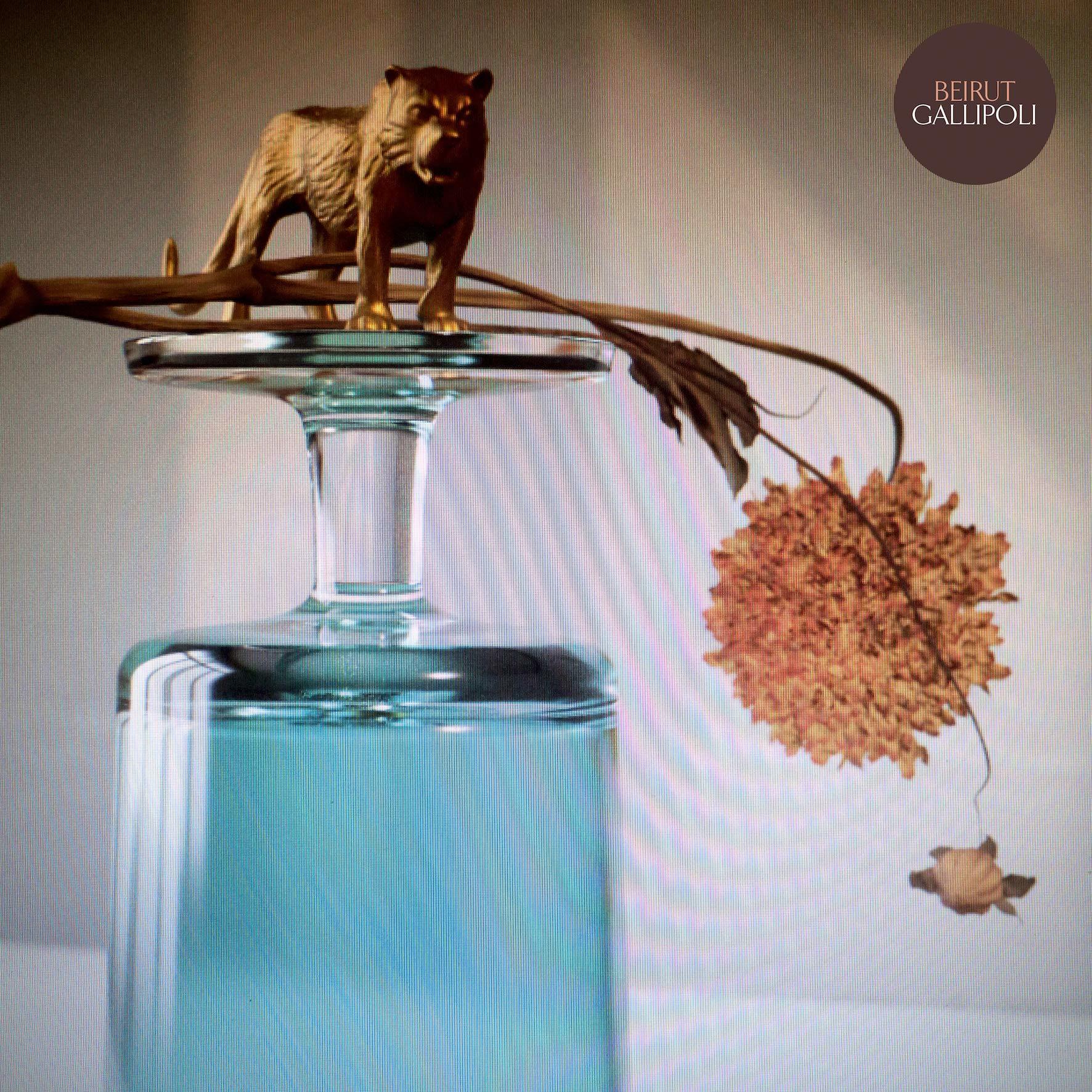 Ein goldener Tiger auf einem Glas mit einer getrockneten Blume. Der Hintergrund ist eine verschwommene, helle Farbe.