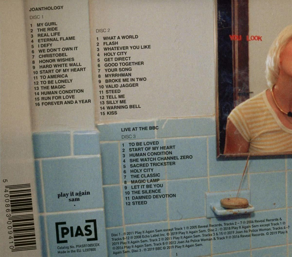 CD mit mehreren Titeln, eine Frau im Hintergrund und eine blau geflieste Wand.