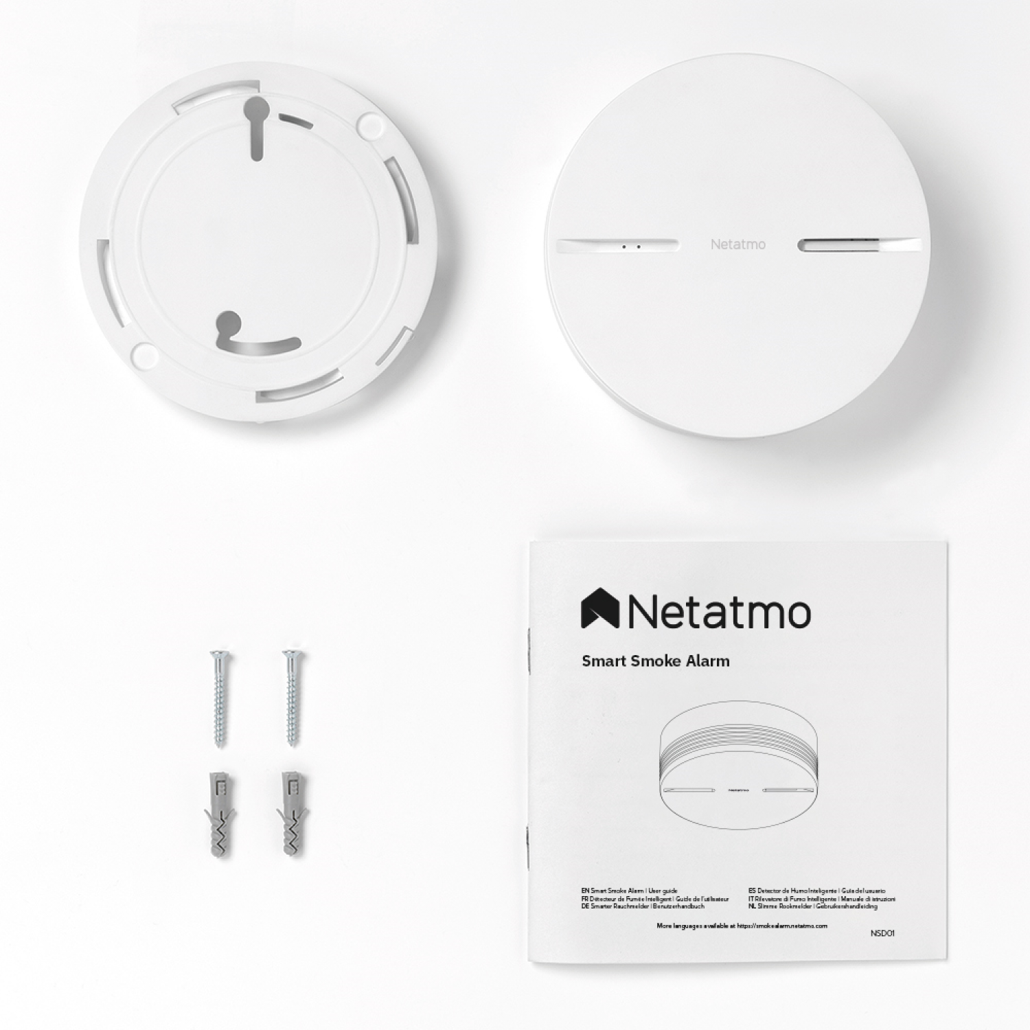 Un kit de alarma de humo con base, alarma, tornillos y manual, todo sobre una superficie blanca.