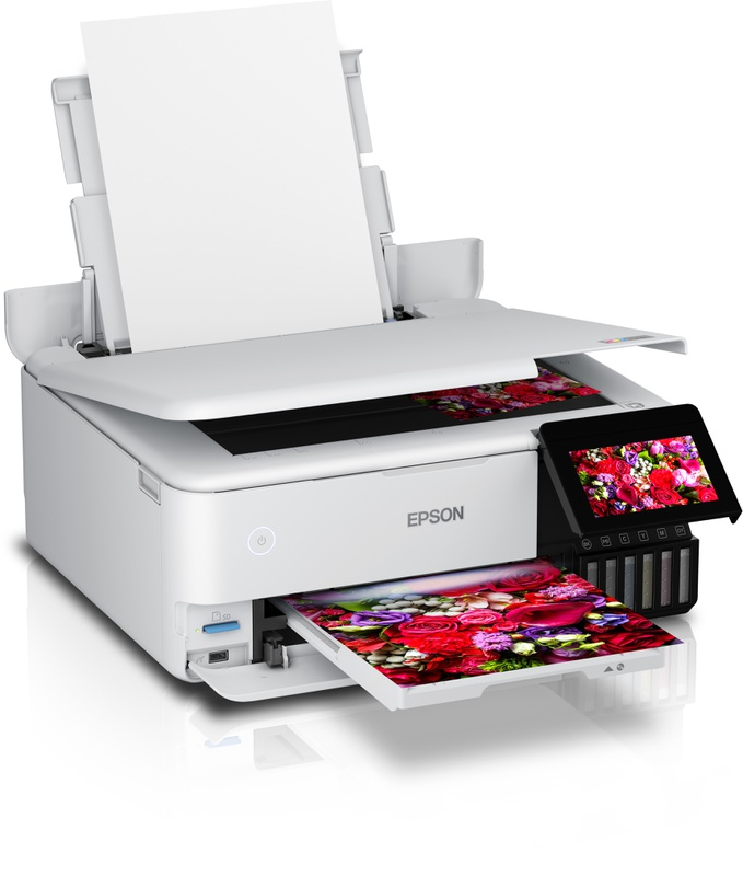 A white printer with a display showing a colorful floral print and paper in the tray.