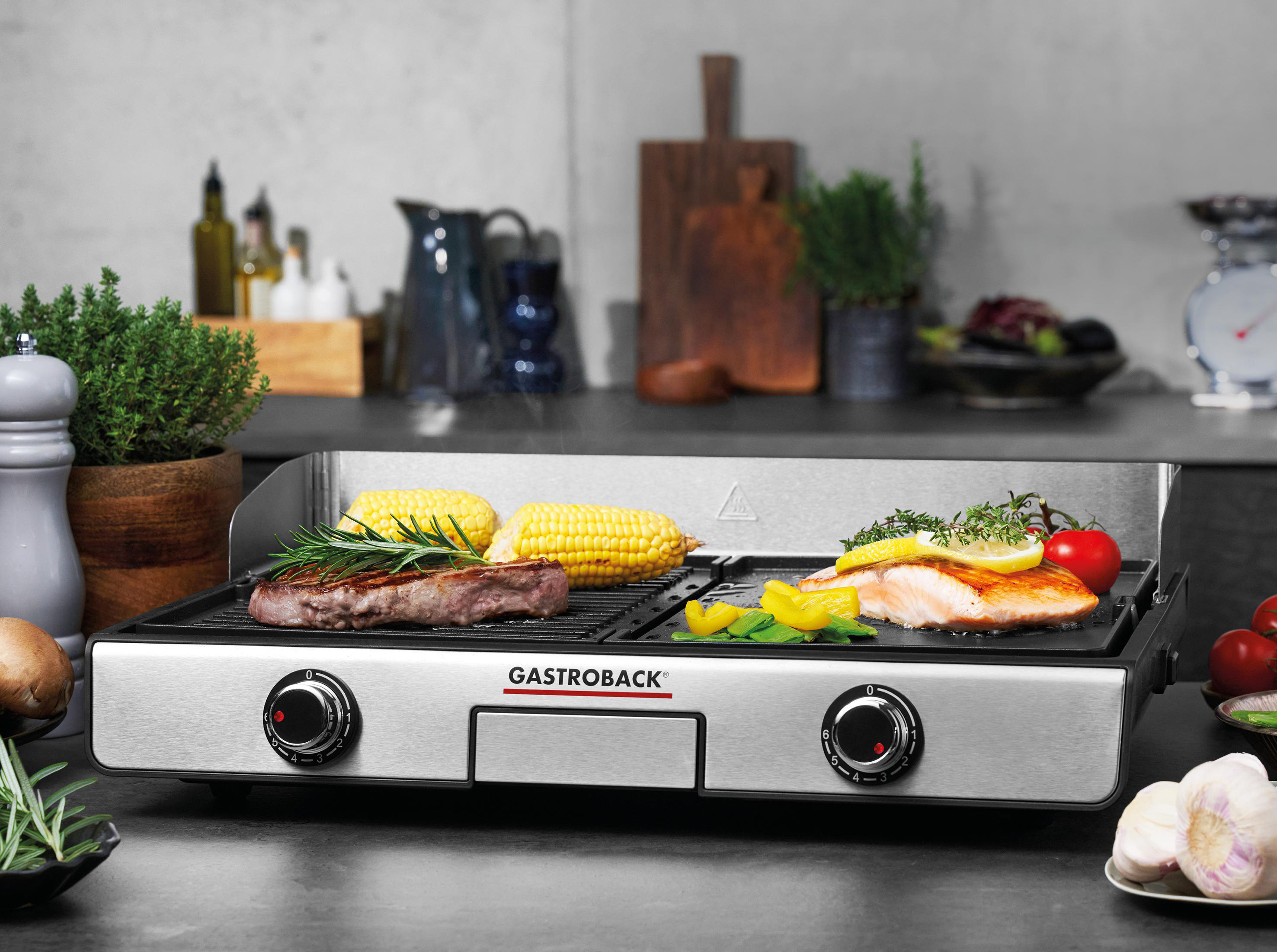 Ein Grill mit Steak, Mais und Fisch, mit Tomaten und Zitrone, in einer Küchenumgebung.