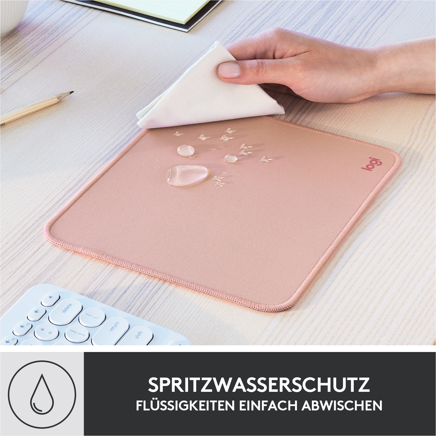 Ein rosa Mauspad mit einem weißen Tuch und Wassertropfen darauf.