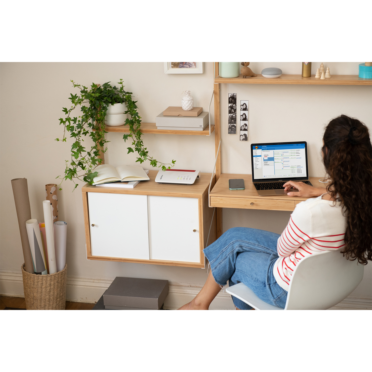 Donna a una scrivania con un laptop. Libri, piante e altri oggetti sulla scrivania.