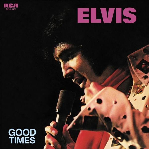 Elvis Presley mikrofonba énekel, világos, fekete pöttyös öltönyt visel.
