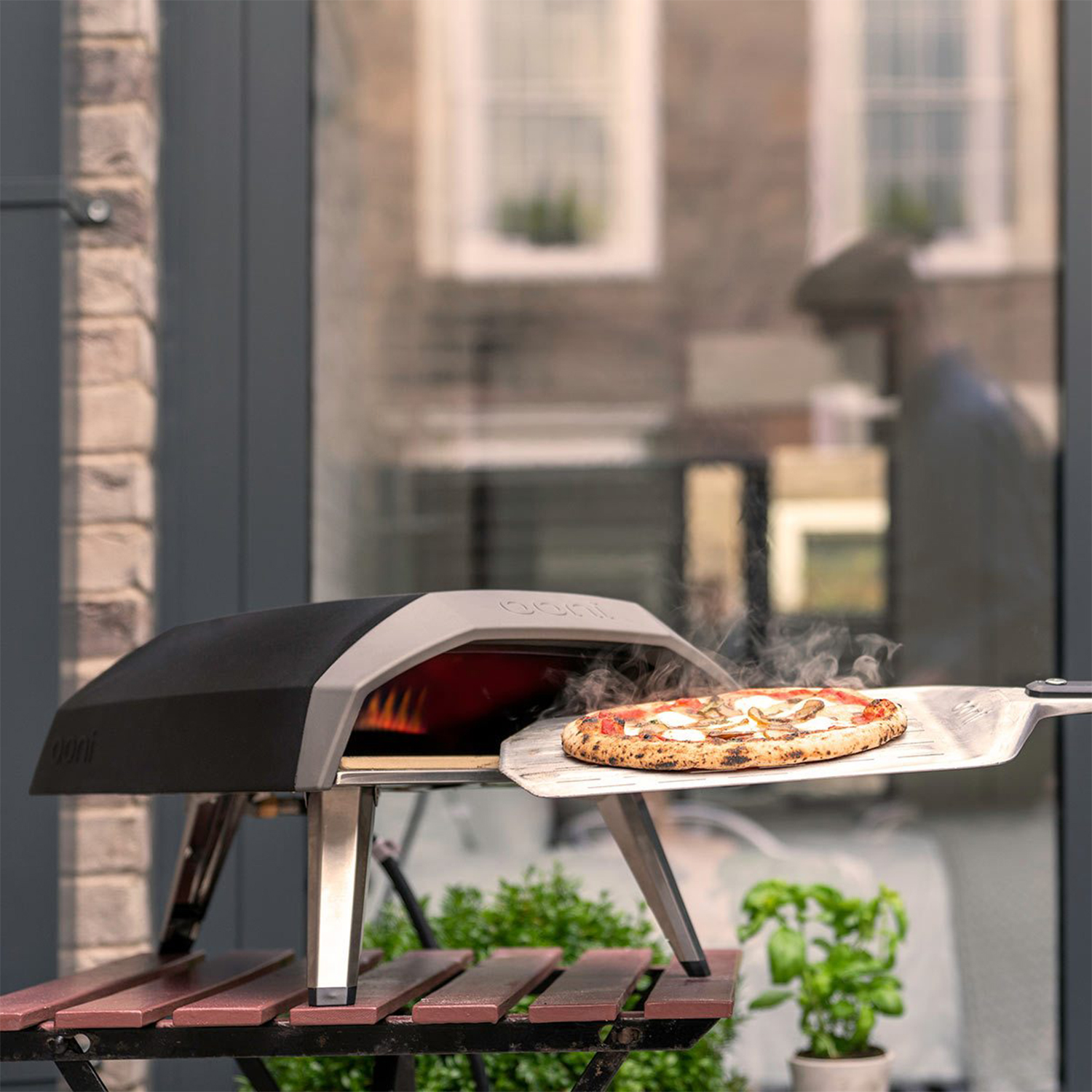 Una pizza viene rimossa da un forno per pizza portatile nero con una pala di metallo.