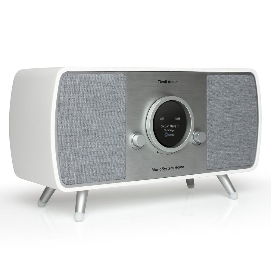 Un sistema musicale Tivoli Audio bianco e argento. Ha uno schermo, due manopole e altoparlanti. Poggia su gambe argentate.