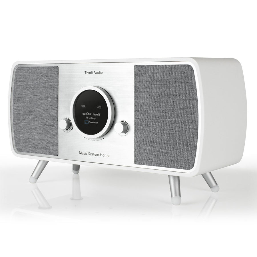 Un sistema musicale Tivoli Audio bianco e argento. Ha uno schermo che mostra l'ora e le informazioni sulla canzone. È su gambe d'argento.