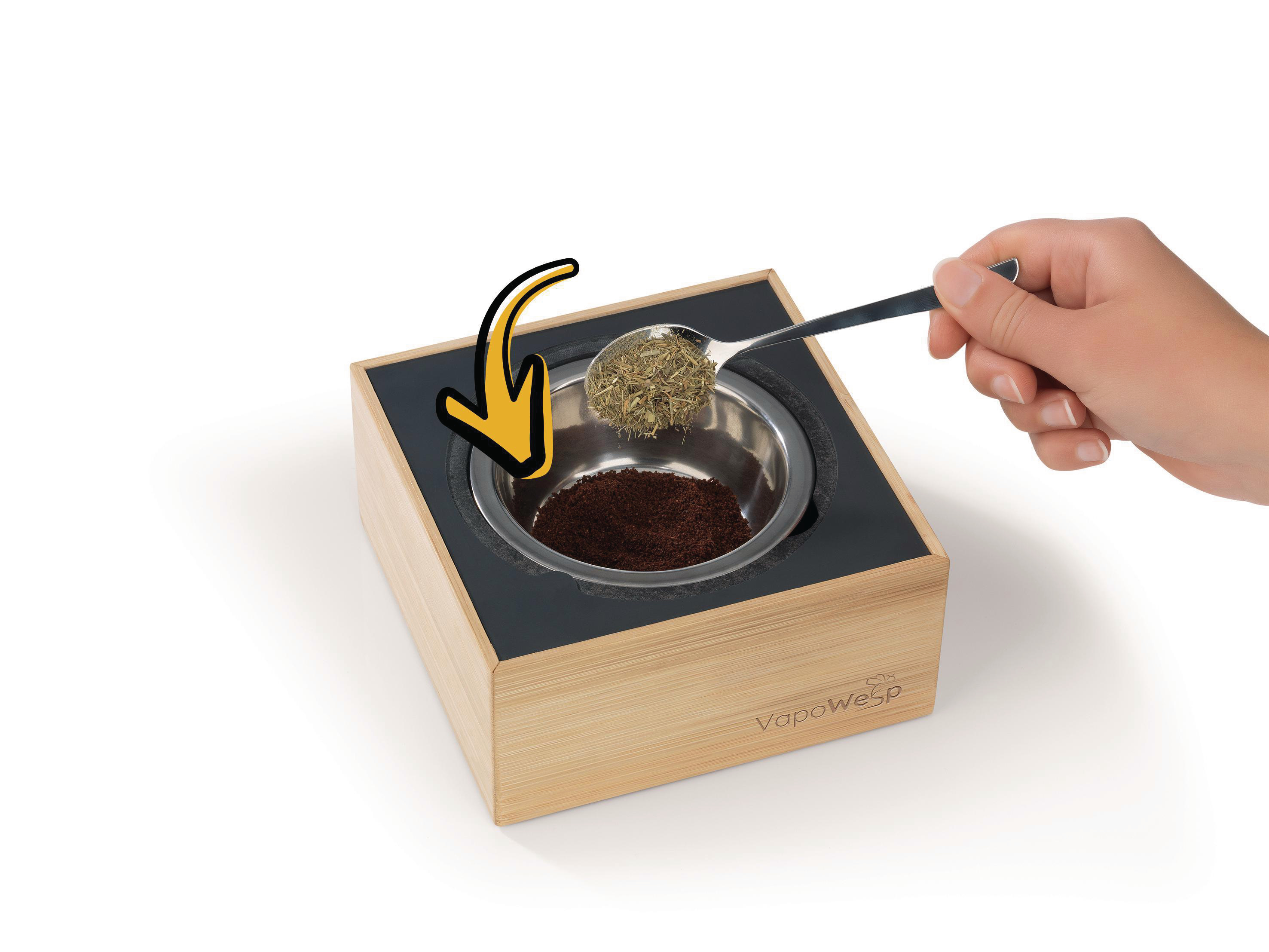 Hand fügt Kräuter in eine Holzkiste, mit Metallschüssel und VapeWesp-Logo hinzu.