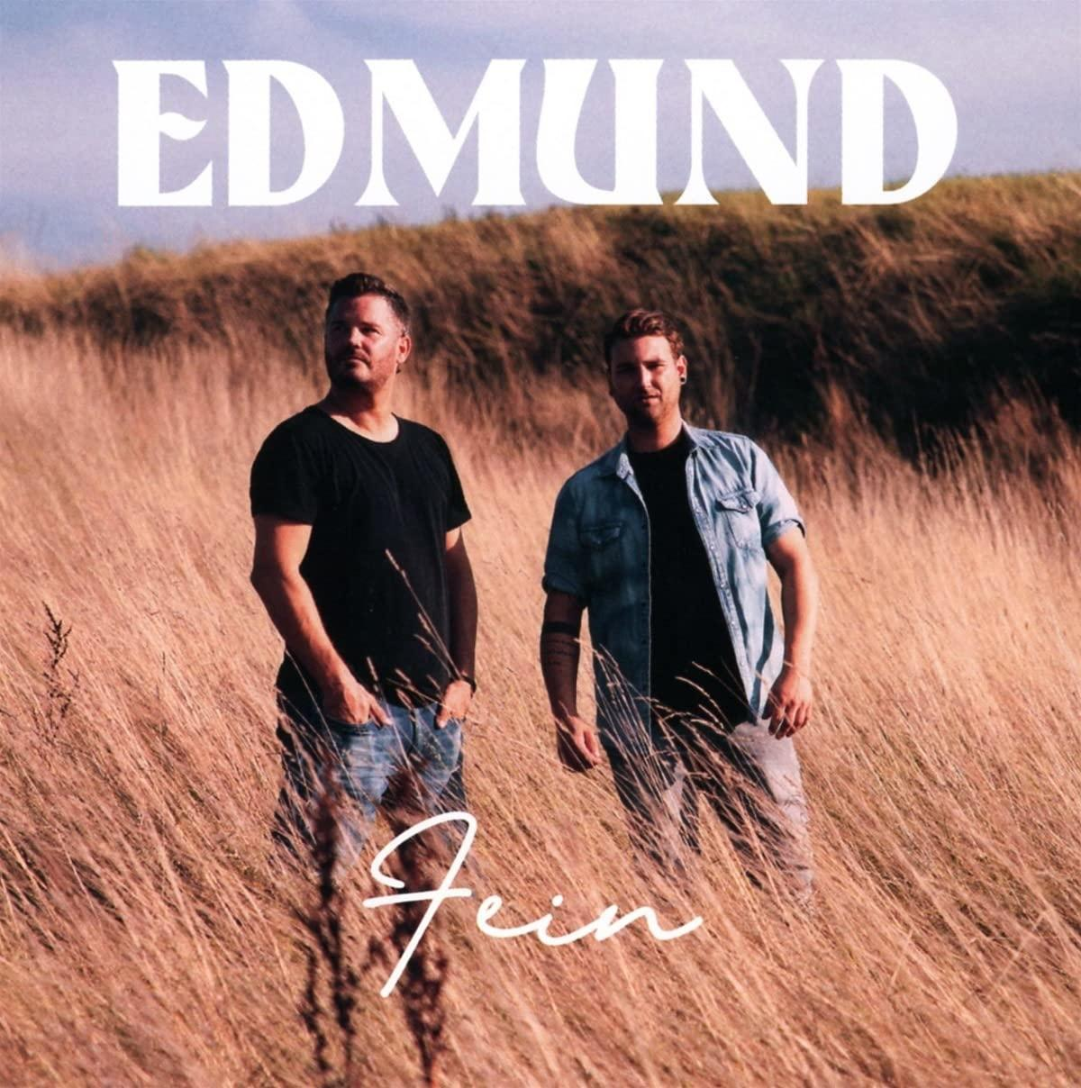 Zwei Männer stehen in einem Feld mit hohem Gras. Text: EDMUND, Fein.