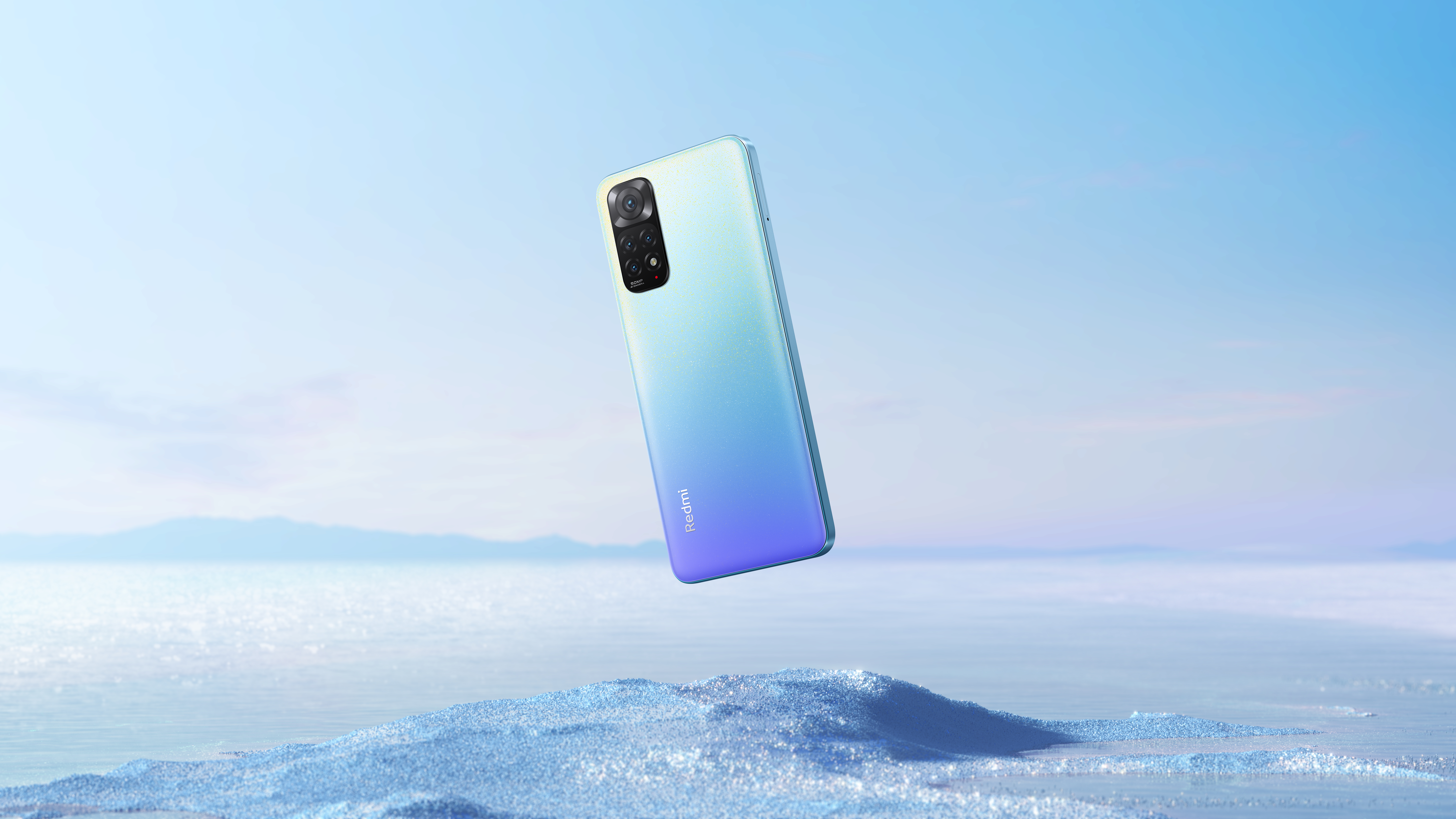 Ein Telefon in der Luft, blau und lila mit einer Kamera. Der Hintergrund ist ein blauer Himmel und weißer Schnee.
