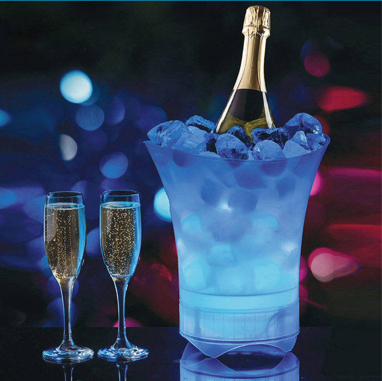 Champagne bottle in ice bucket with glasses. Blue lighting effect in the background, blurring the scene.