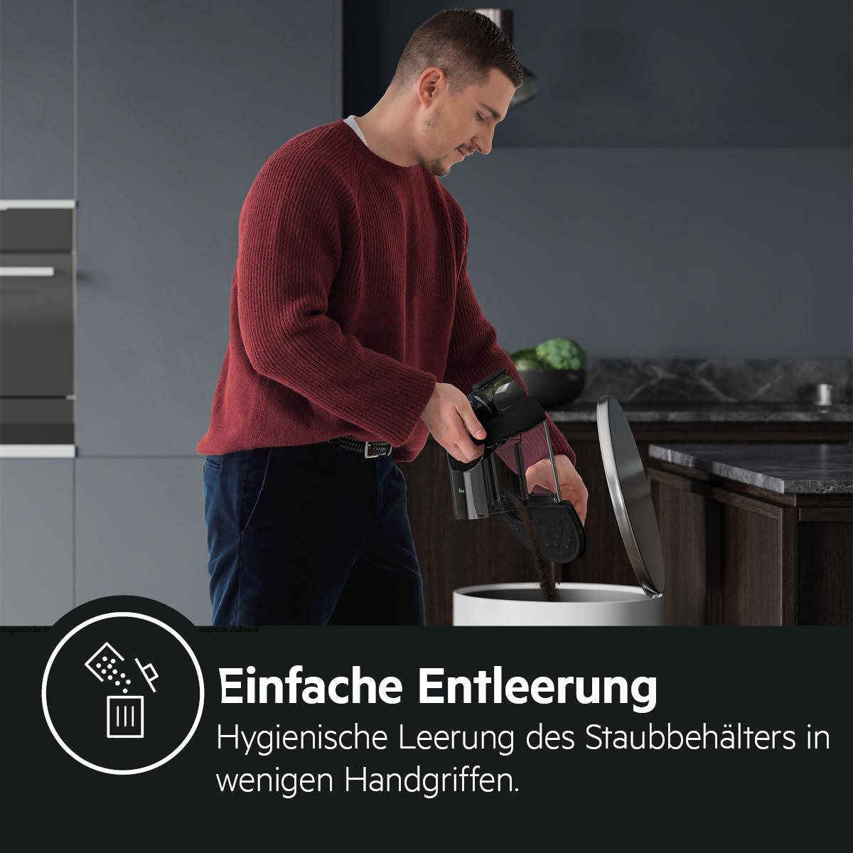 Ein Mann leert einen schwarzen Staubsaugerbehälter in einen weißen Mülleimer.