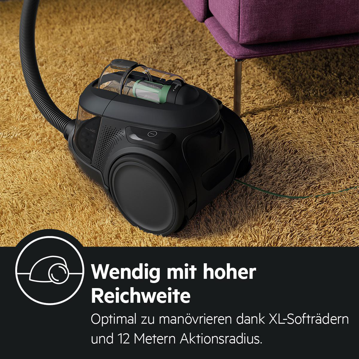 Ein schwarzer Staubsauger auf einem gelben Teppich. Text: 'Wendig mit hoher Reichweite', 'XL-Softrädern'.