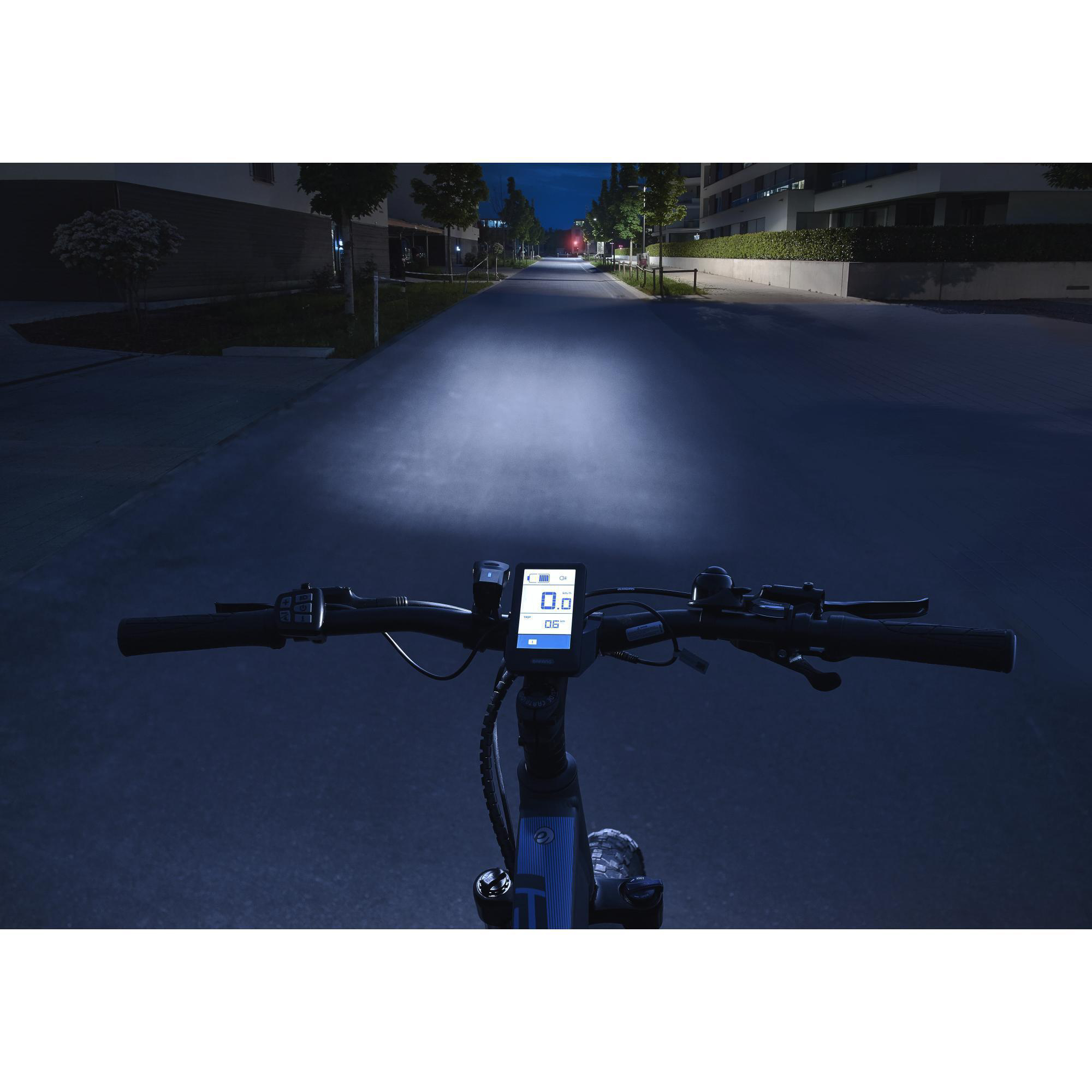 Ego-Perspektive beim Fahrradfahren bei Nacht. Helle Scheinwerfer beleuchten den Weg.