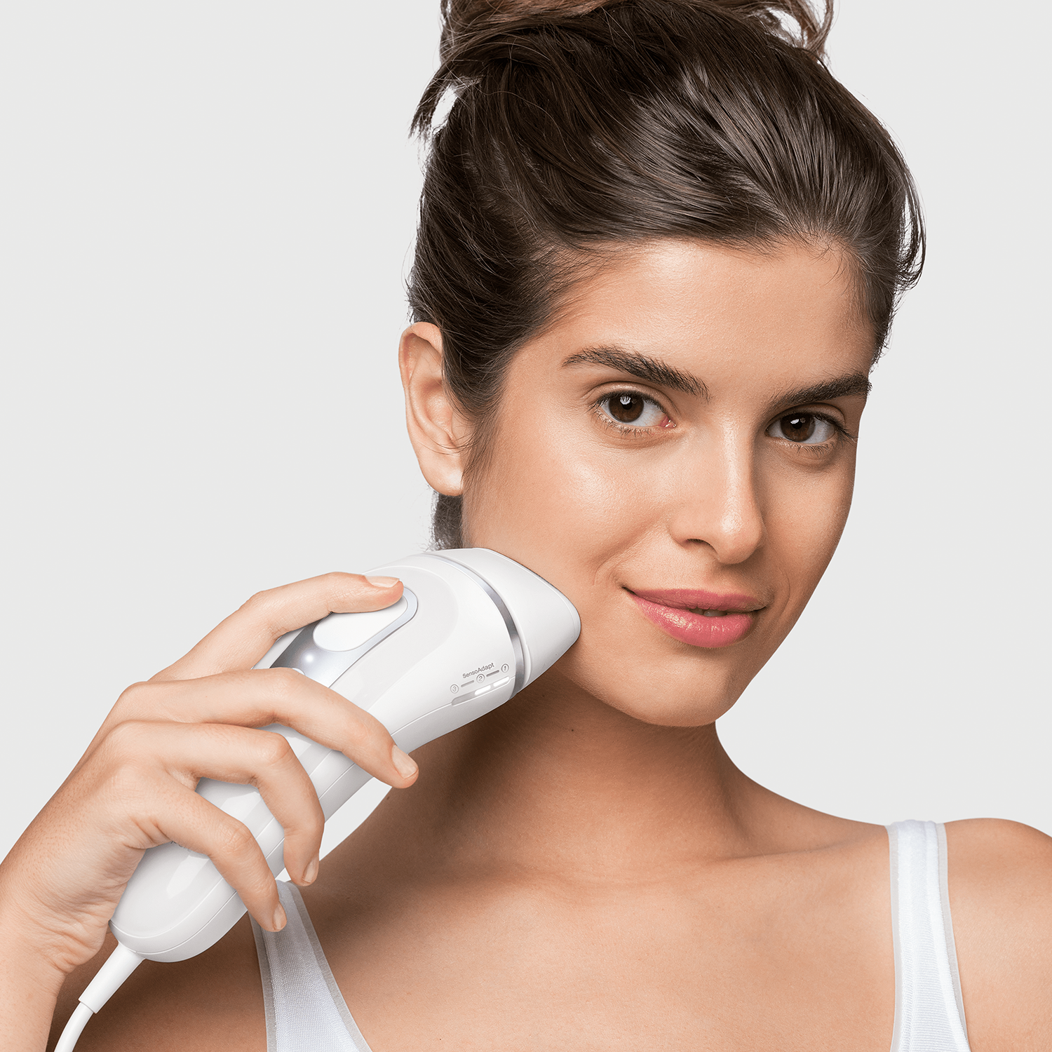 Woman using a white IPL hair removal device on her face.