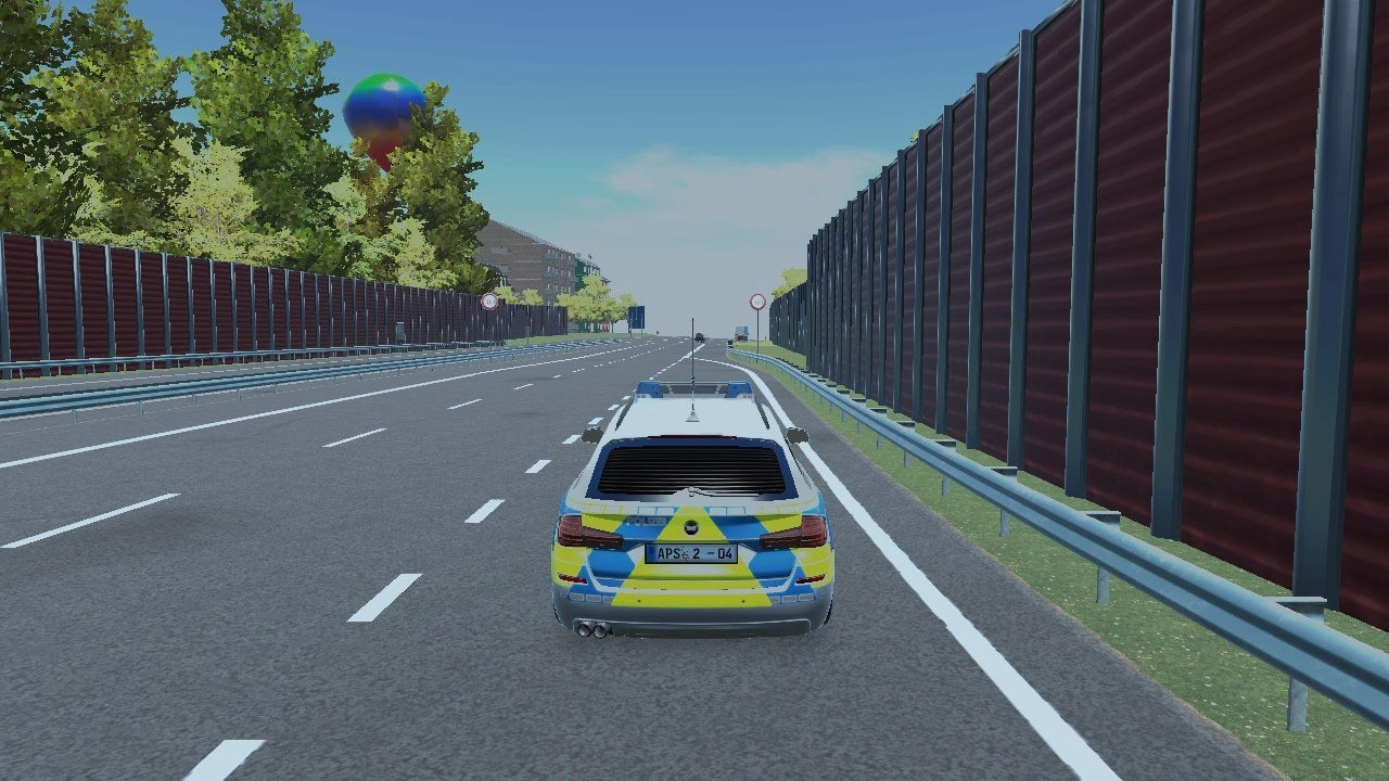 Voiture de police roulant sur une autoroute, barrière antibruit en arrière-plan, ciel bleu et arbres.
