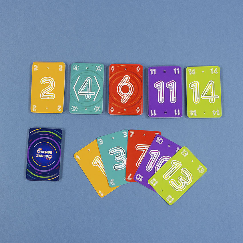 Karten mit bunten Zahlen aus einem Brettspiel, angeordnet auf blauer Oberfläche.