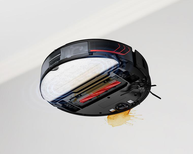 Roboter-Staubsauger auf weißer Oberfläche, mit Kaffeefleck.
