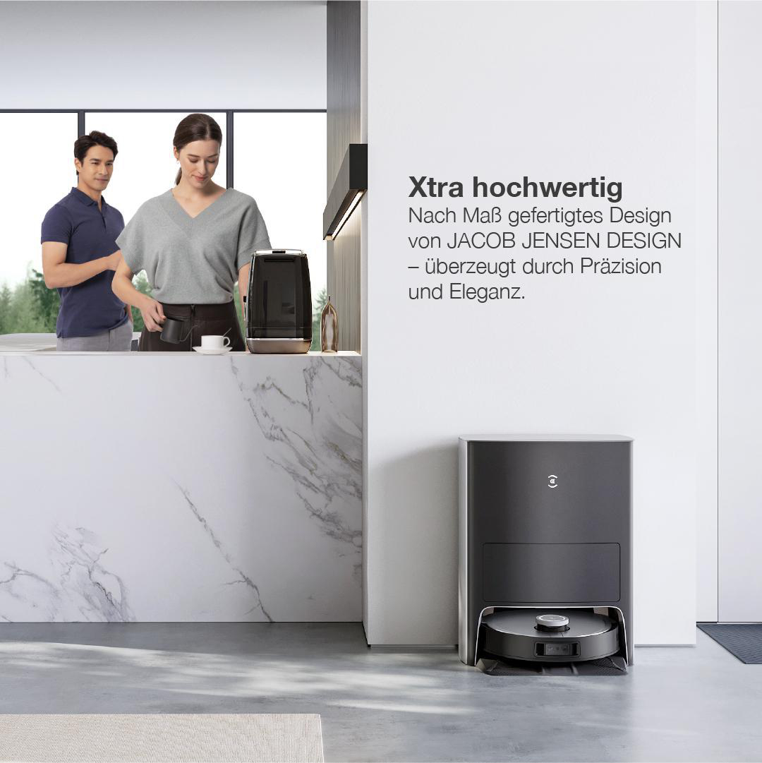 Zwei Personen in einer Küche mit einem Roboter-Staubsauger unten.