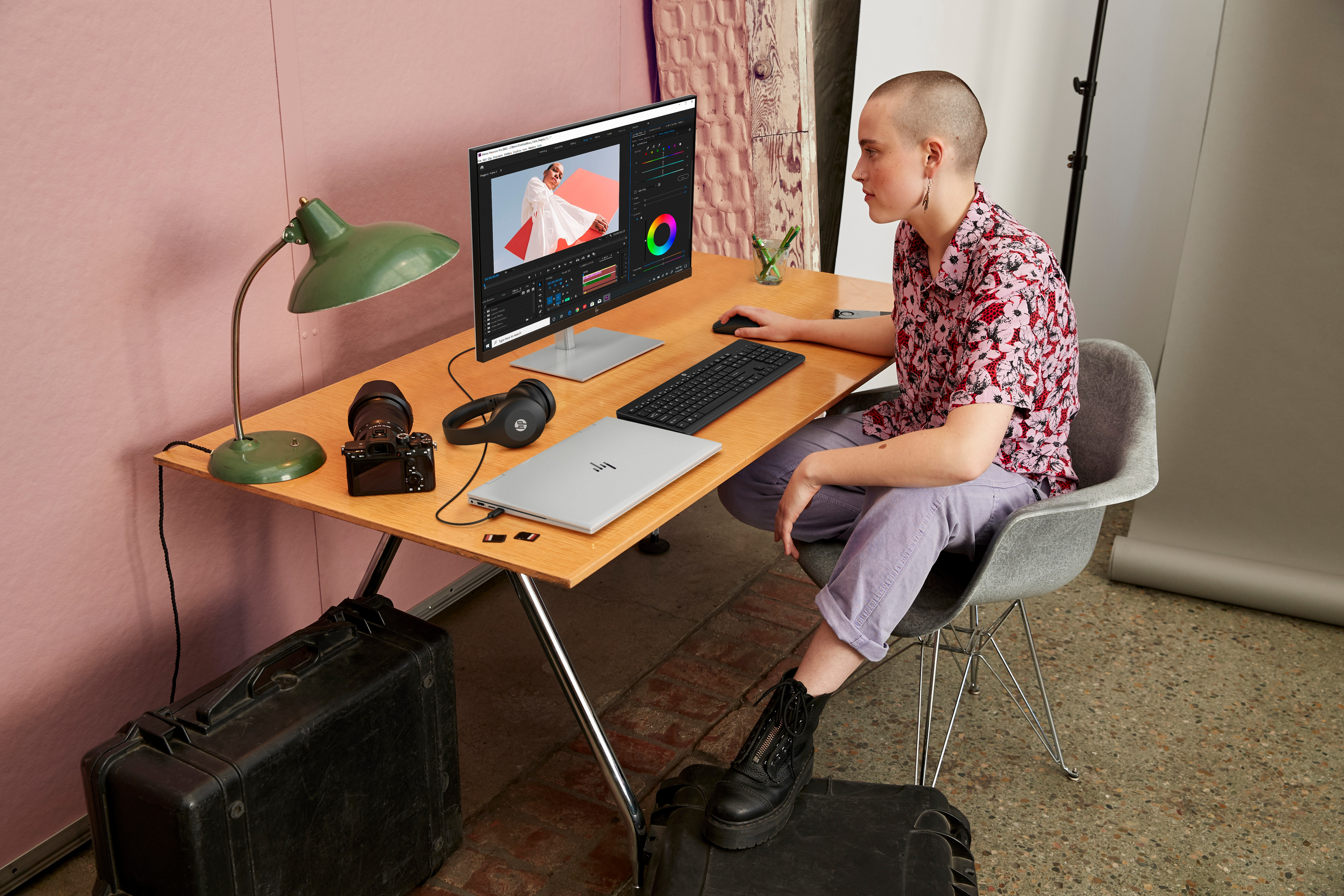 Una persona con la cabeza rapada está trabajando en un escritorio con un monitor y un portátil.