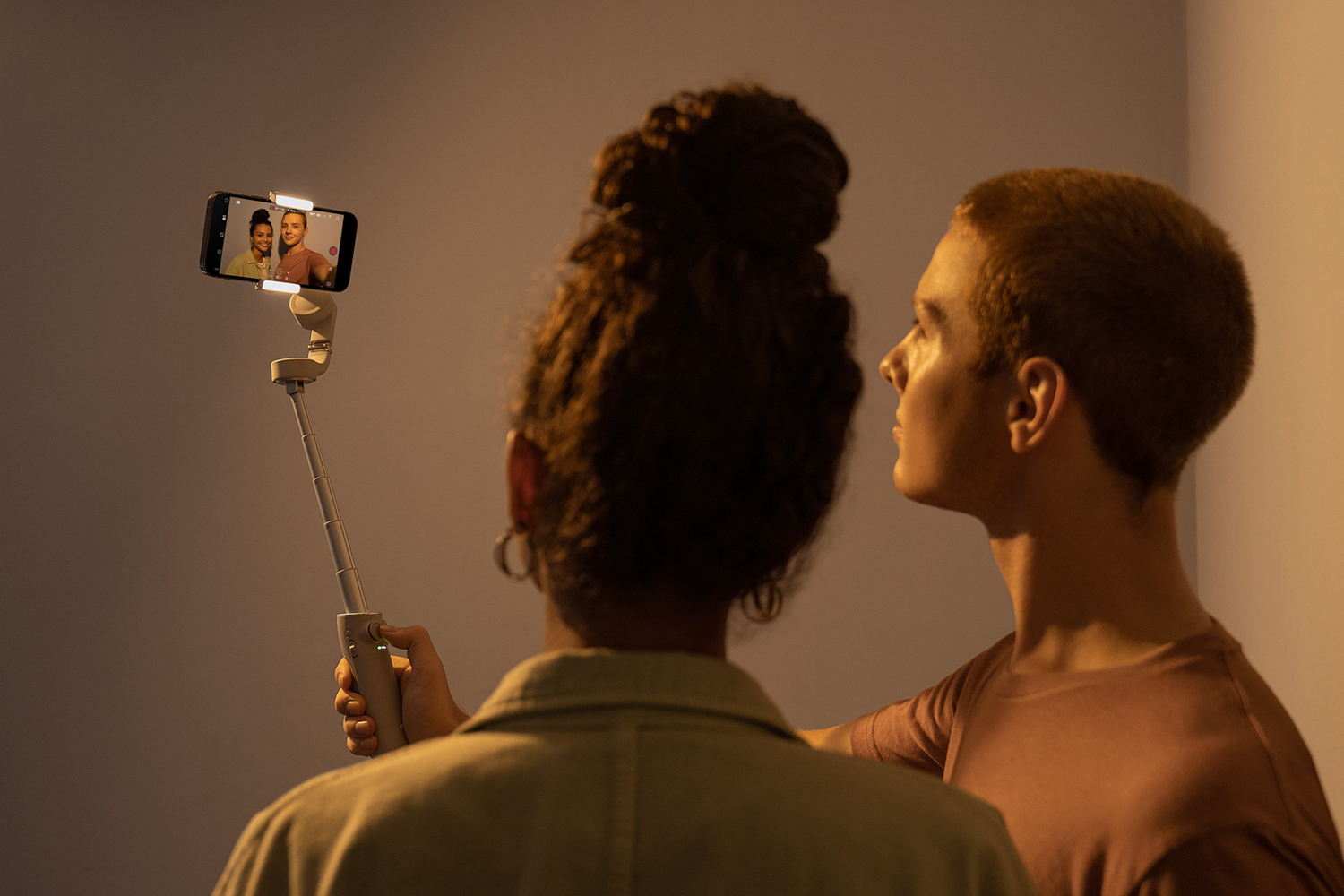 Twee mensen die een selfie maken met een telefoon en een selfiestick.