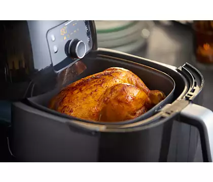 An air fryer with a cooked chicken inside.