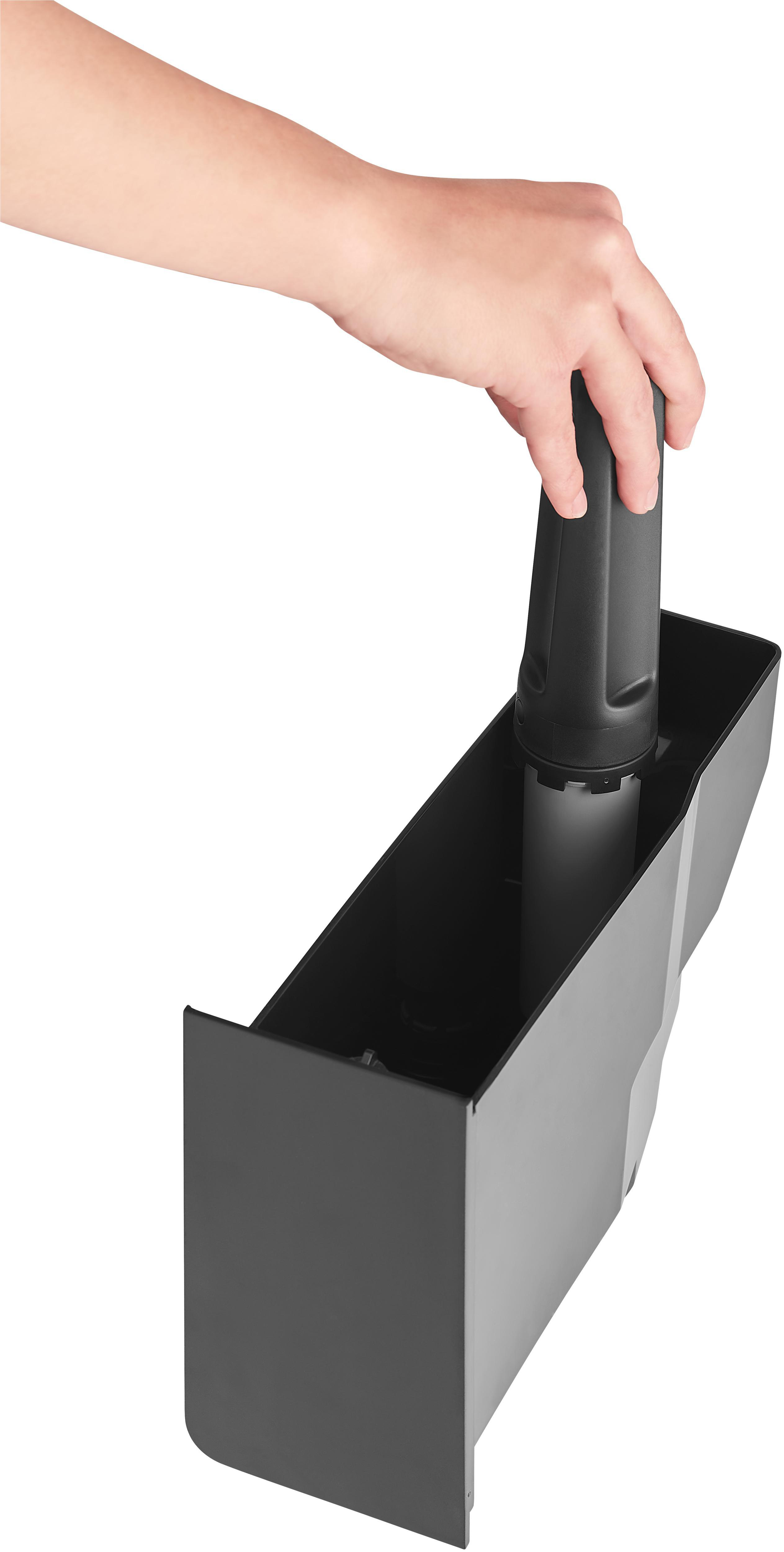 Eine Hand, die einen schwarzen Filter hält. Der Gegenstand ist in einem schwarzen Behälter.