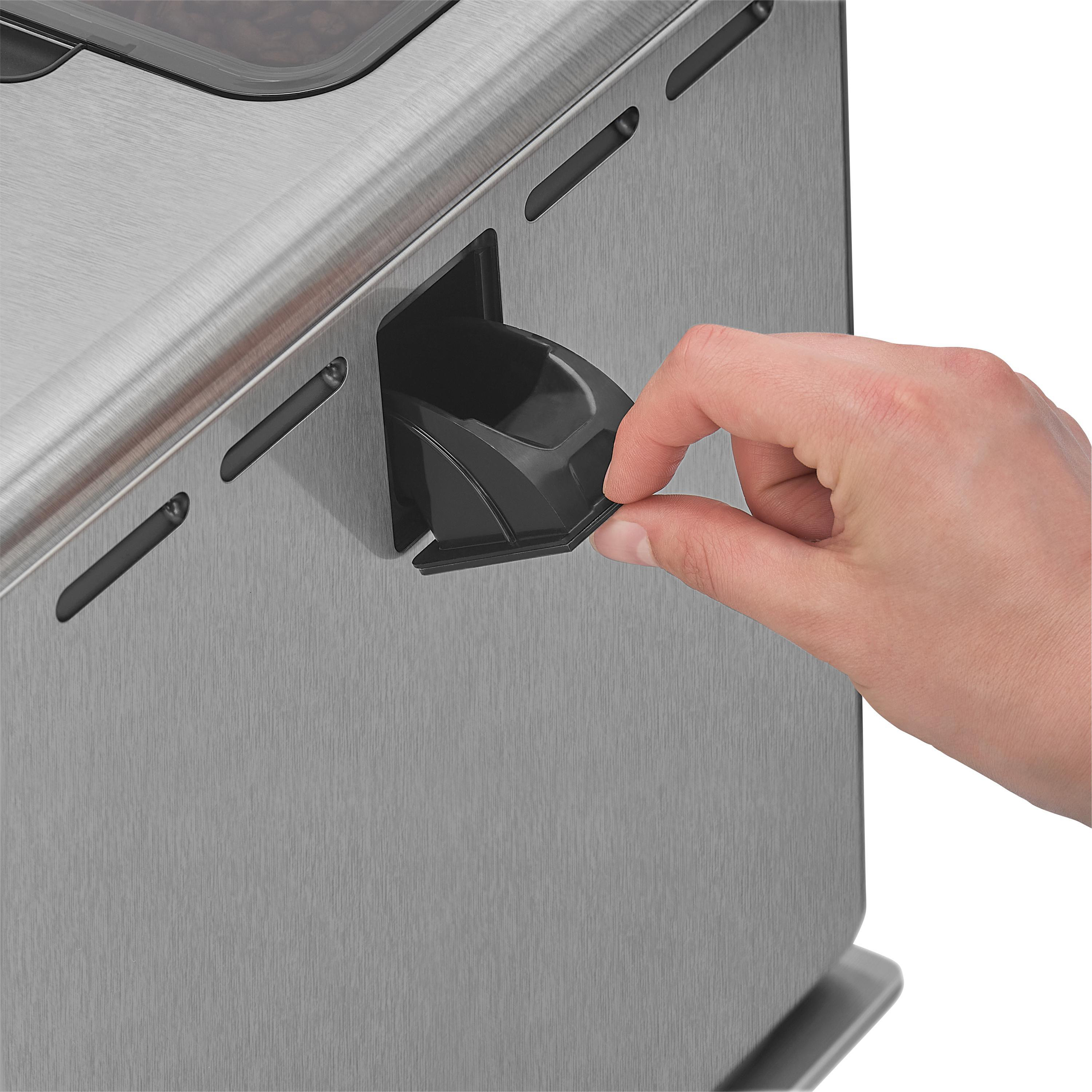 Eine Hand entnimmt einen schwarzen Behälter aus einer Kaffeemaschine aus Edelstahl.
