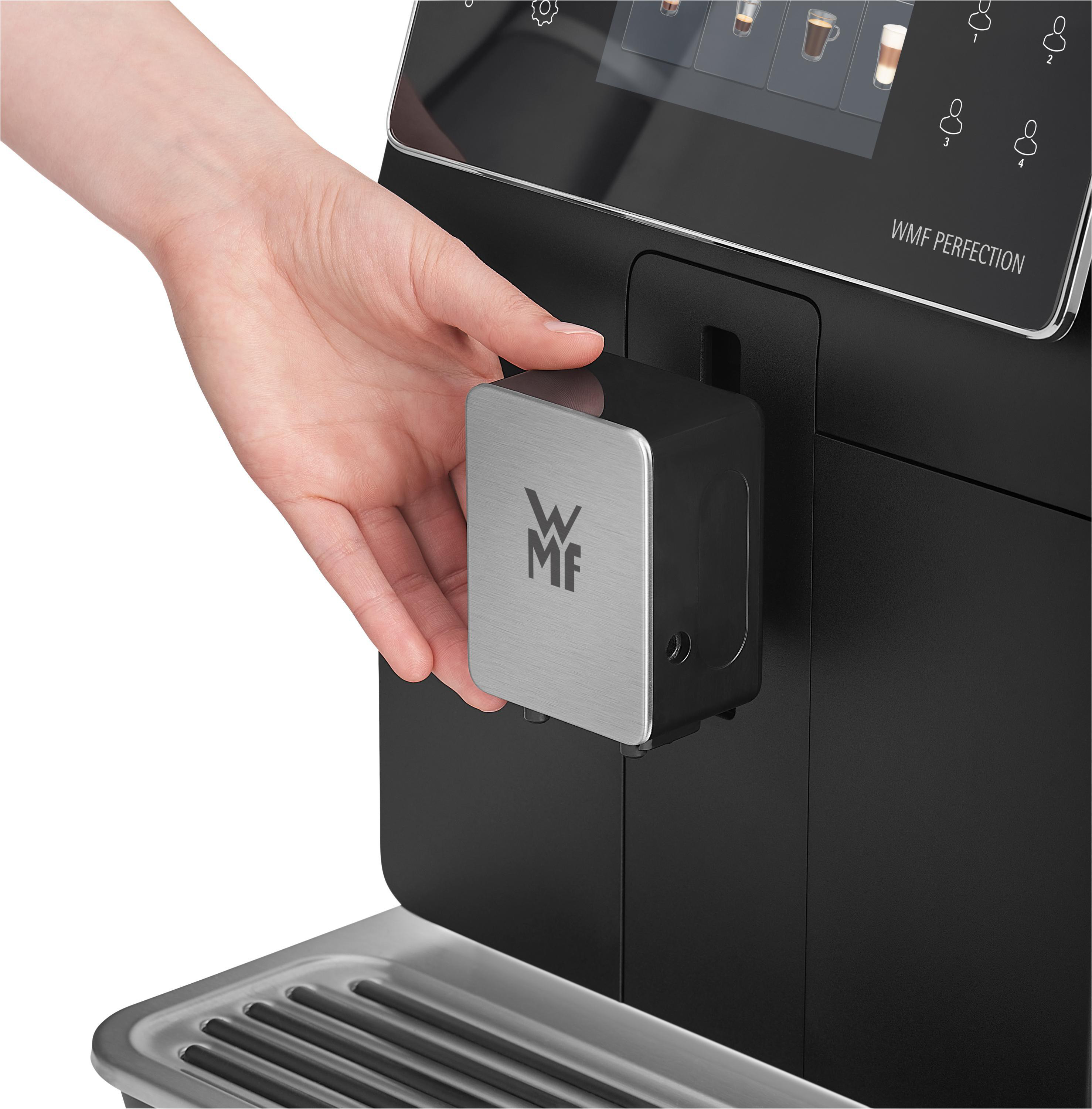 Eine Hand setzt den Wassertank einer schwarzen WMF Perfection Kaffeemaschine ein.