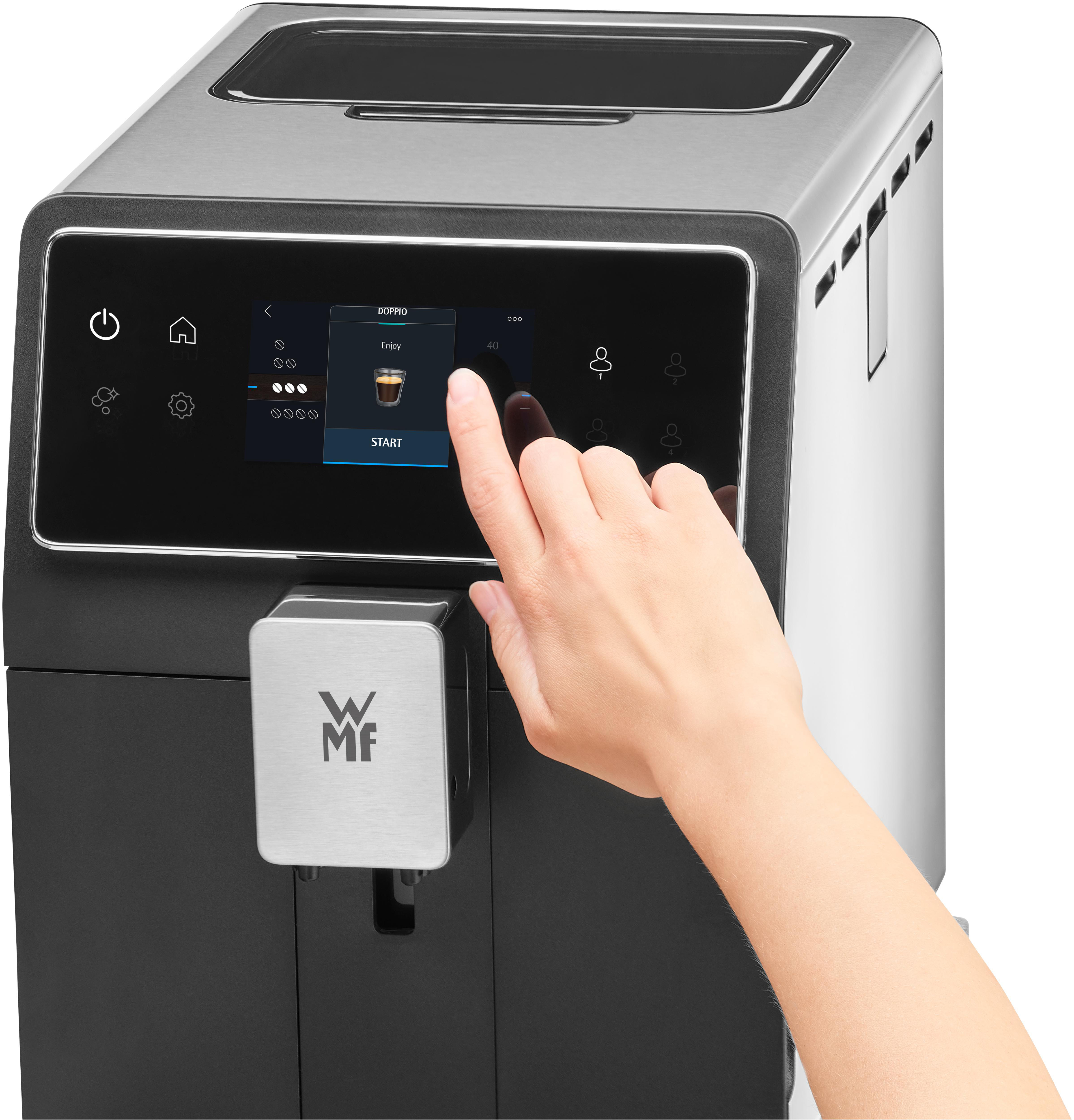 Eine Hand berührt die Starttaste auf dem Touchscreen einer Kaffeemaschine.